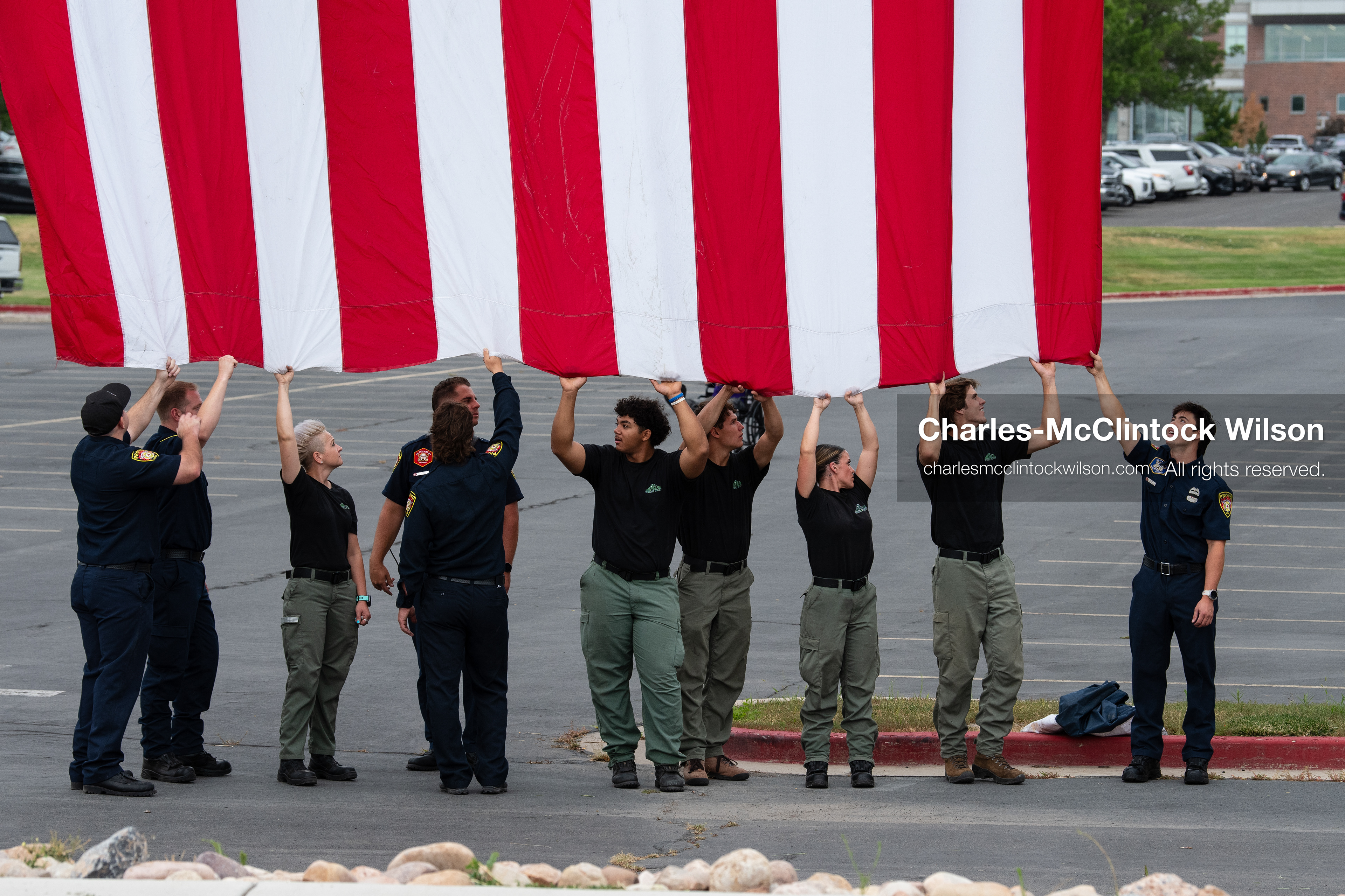 First responders stand in a row holding the bottom edge of a large American flag outside the UCCU Center at Utah Valley University in Orem, Utah, on Wednesday, July 29, 2026. More than 300 people came to the public memorial ceremony to honor Provo Fire Captain Spencer Long, his wife Katrina, and three of their sons, who died after a flash flood hit their campsite near the Sunglow Campground in Wayne County. (Photo by Charles-McClintock Wilson/Sipa USA)