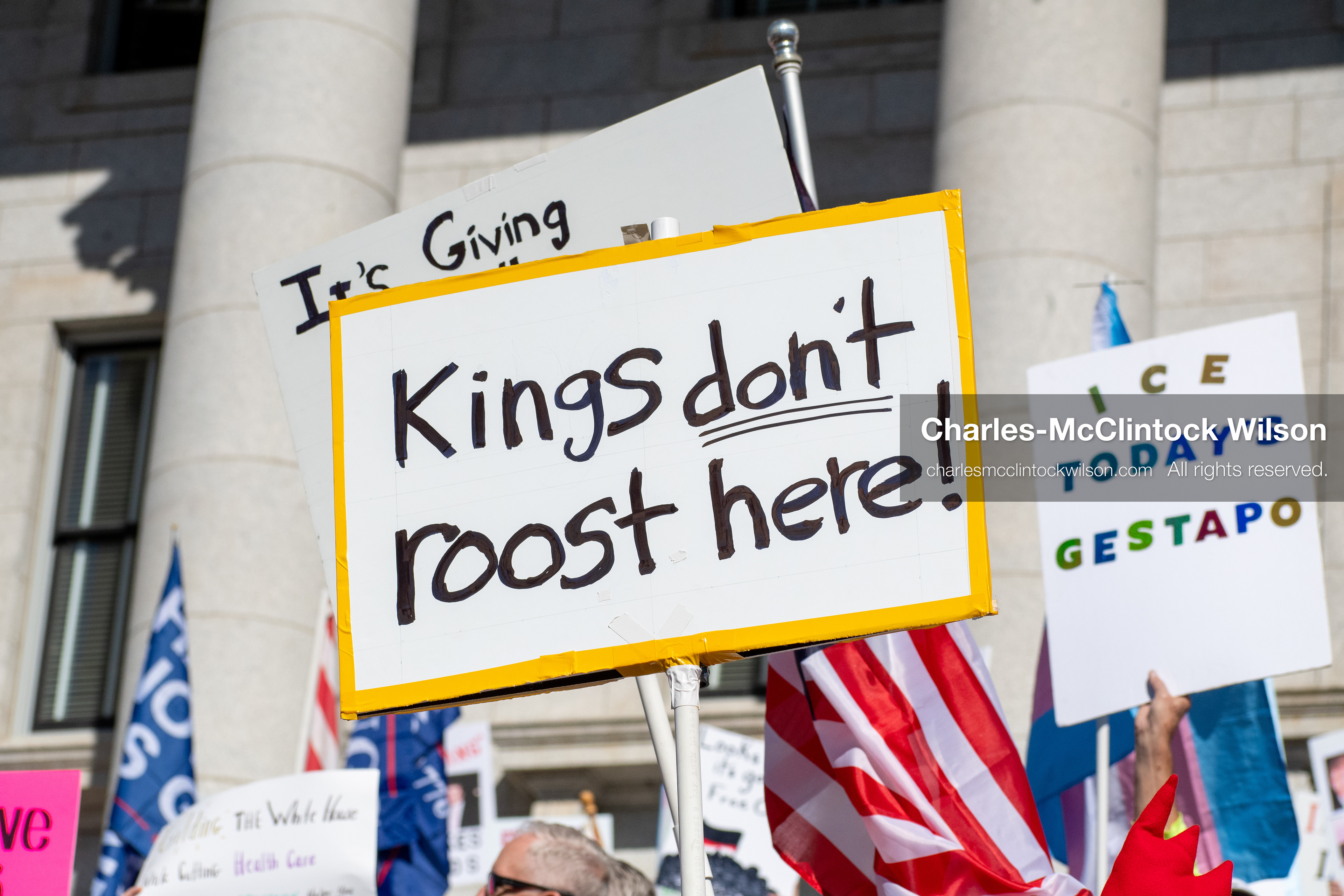 October 18, 2025, Salt Lake City, Utah, USA: A demonstrator raises a placard during a "No Kings" protest held at the Utah State Capitol. Other participants and signs are visible in the background during the public gathering.