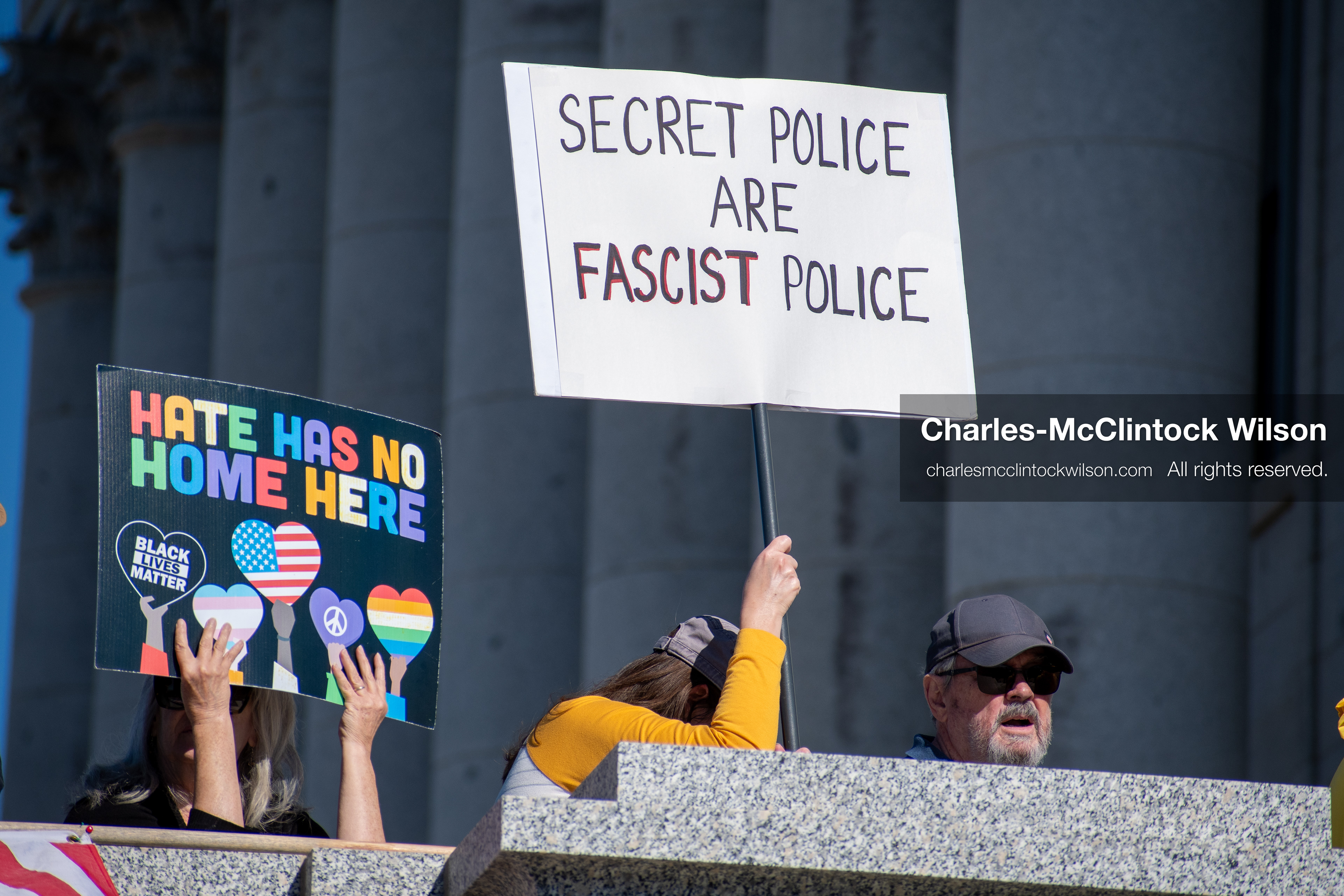 October 18, 2025, Salt Lake City, Utah, USA: A demonstrator raises a placard during a "No Kings" protest held at the Utah State Capitol. Other participants and signs are visible in the background during the public gathering.