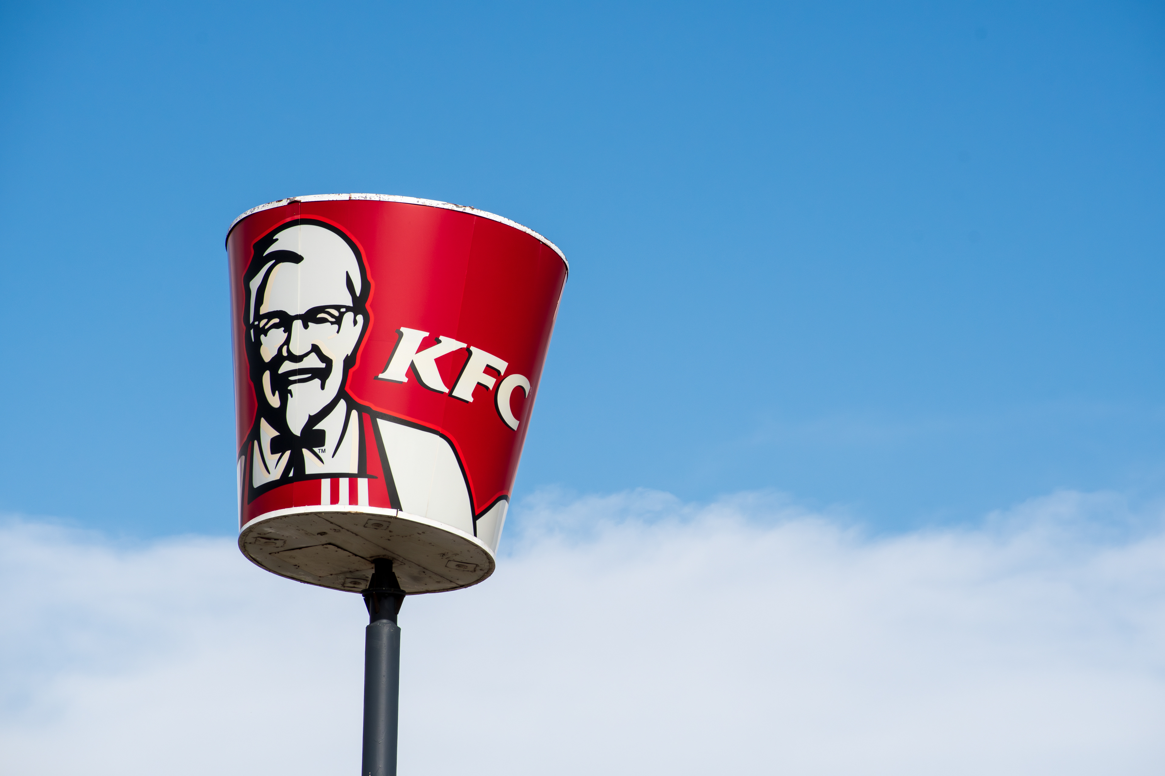 Spanish Fork, Utah, USA – May 28, 2025: A “Bucket of chicken” sign stands on a pole outside a Kentucky Fried Chicken (KFC) restaurant, highlighting the fast-food chain’s iconic menu item and branding.