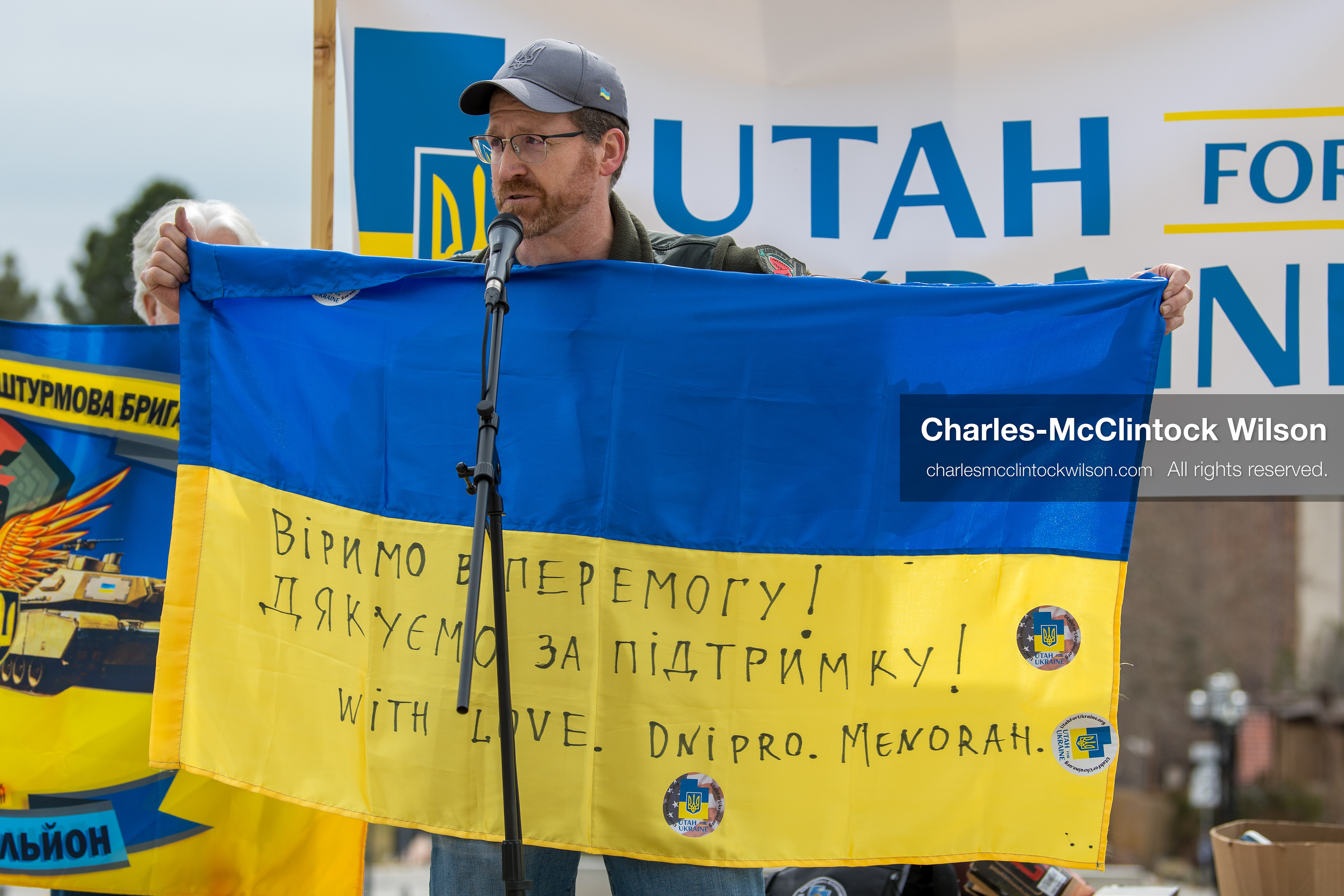 February 28, 2026, Salt Lake City, Utah, USA: NATHANIEL SANDERS, a Salt Lake County Deputy District Attorney and vocal advocate for Ukraine, holds a Ukrainian flag with messages of support while speaking during the Stand With Ukraine rally at the Utah State Capitol. The gathering marked the four year anniversary of the full scale Russian invasion of Ukraine and brought community members together in support of Ukrainians and local humanitarian efforts. (Credit Image: © Charles McClintock Wilson/ZUMA Press Wire)