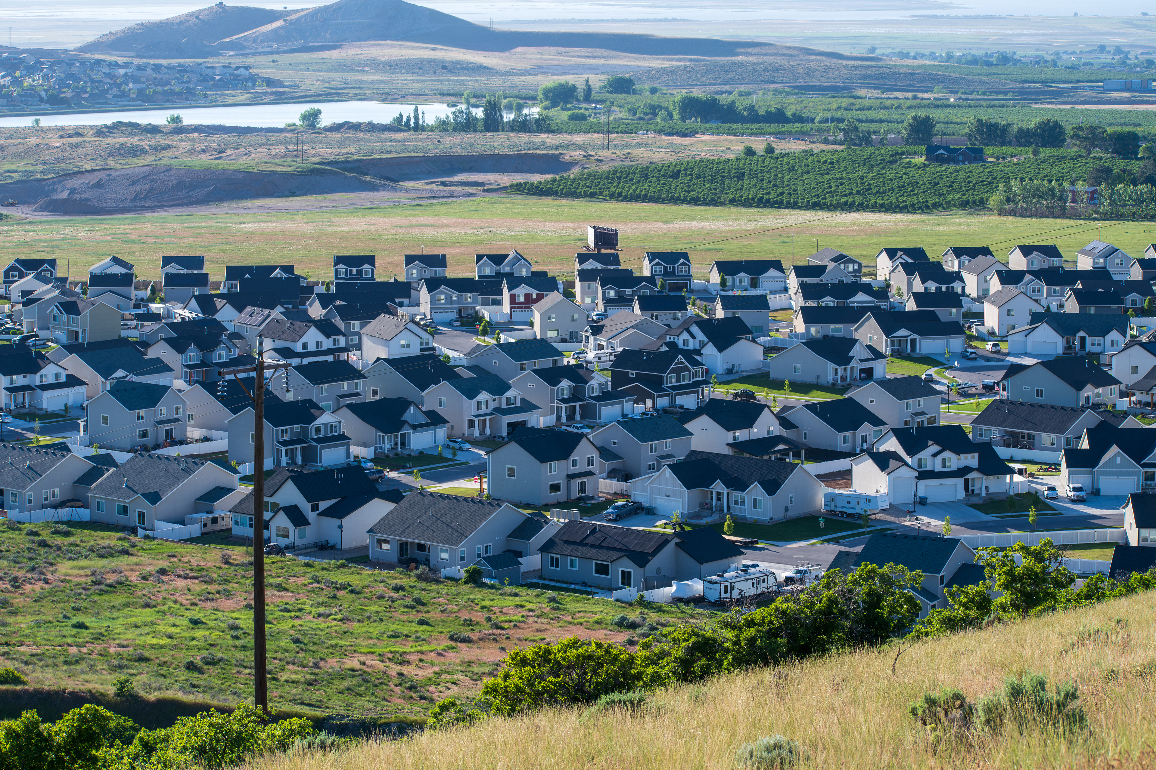 Santaquin, Utah – June 2, 2025: Wide view of a residential neighborhood with a mountainous backdrop and open valley under a clear sky.
