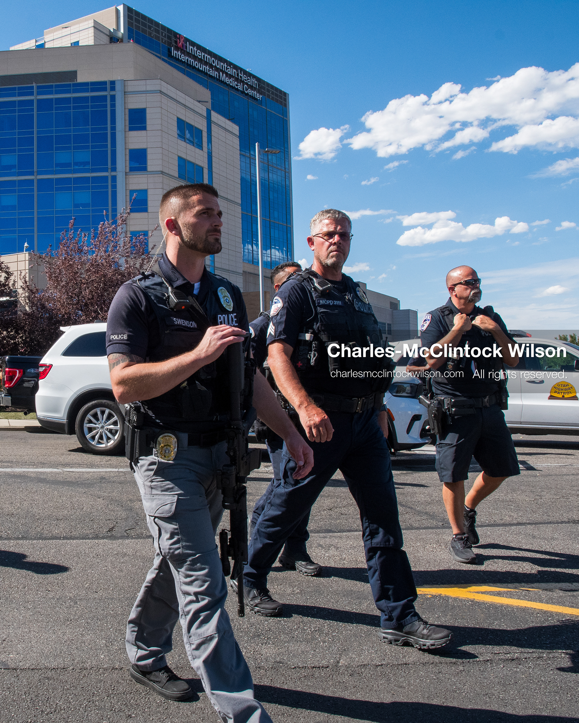 Plainclothes detectives and uniformed law enforcement officers patrol a parking lot checkpoint area outside Intermountain Medical Center in Murray, Utah, United States, on August 17, 2026. Multiple regional police agencies secured the hospital perimeter as a safety precaution after shooting victims were admitted following a fatal shootout outside a funeral service in nearby Kearns. (Photo by Charles-McClintock Wilson/NurPhoto)