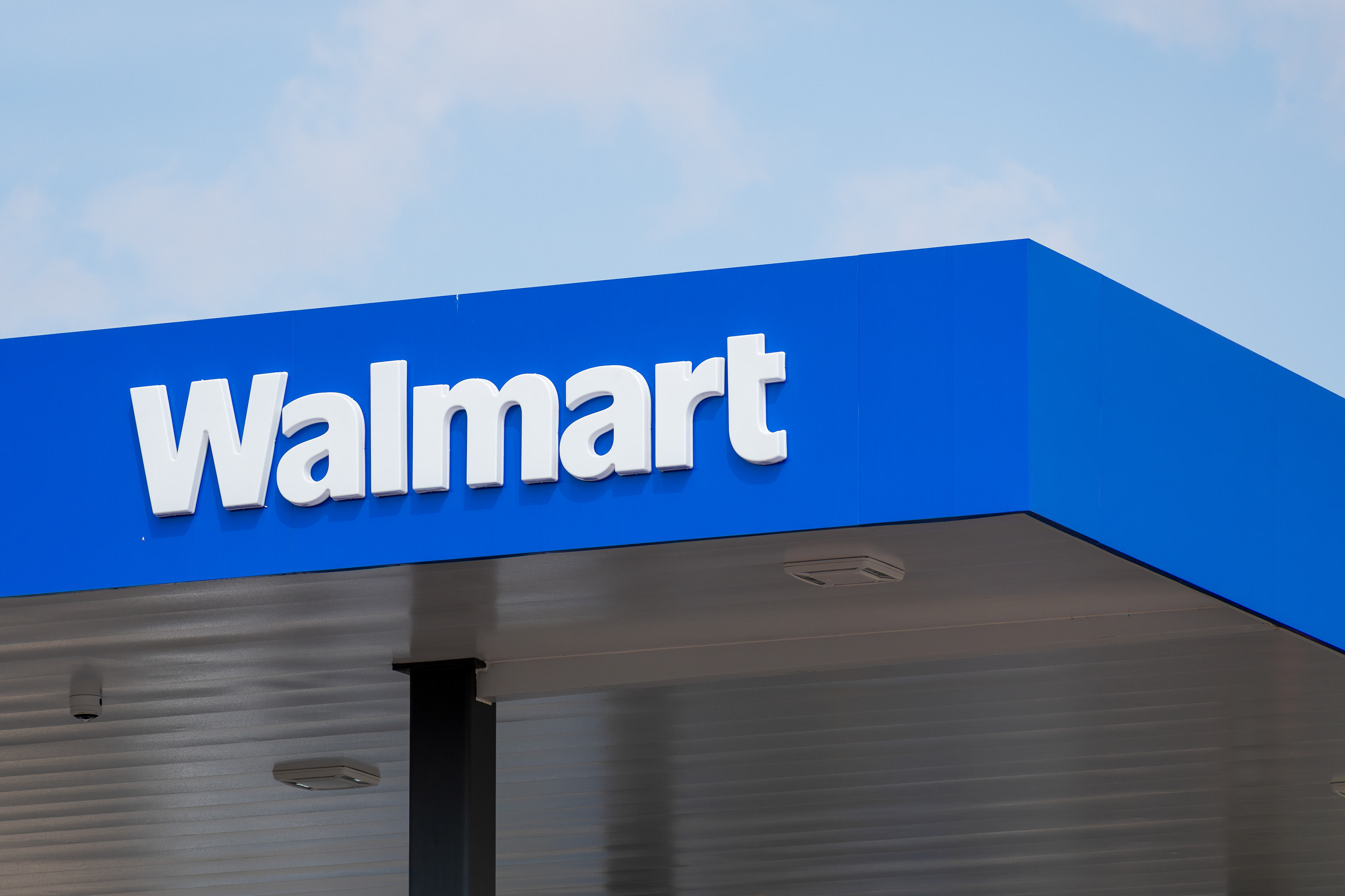 Eagle Mountain, Utah, USA — September 1, 2025: A covered fueling station at Walmart features a blue overhang supported by metal columns. The structure sits beneath partly cloudy skies.