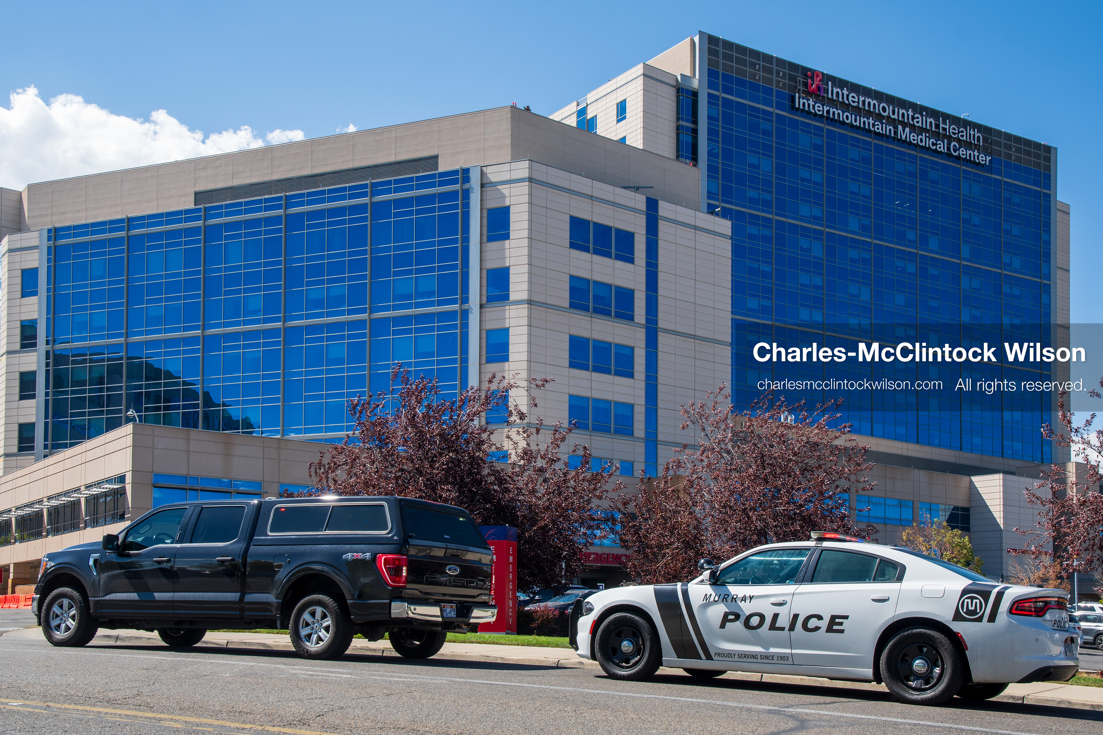 A wide view shows the exterior building facade and parking area of Intermountain Medical Center in Murray, Utah, United States, on August 17, 2026. Multiple regional police agencies secure the hospital perimeter as a safety precaution after shooting victims were admitted following a fatal shootout outside a funeral service in nearby Kearns. (Photo by Charles-McClintock Wilson/NurPhoto)