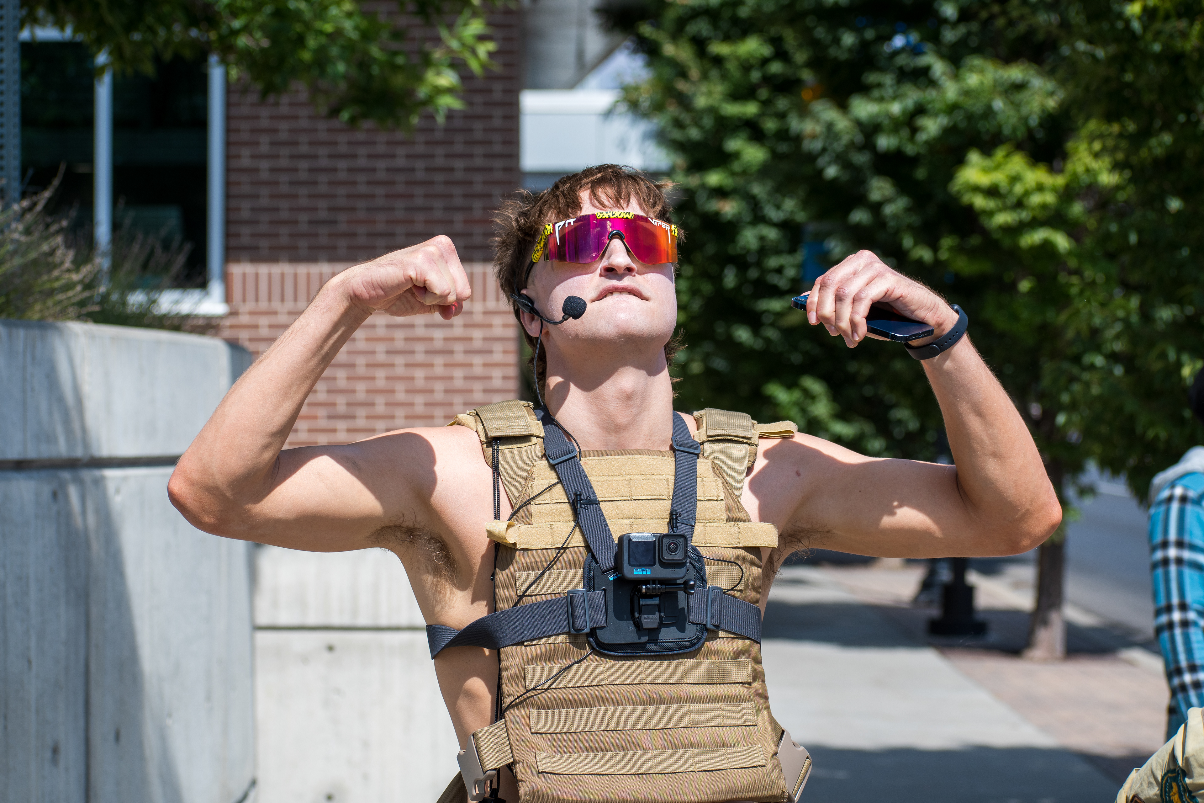September 15, 2025 – Provo, Utah, United States: A demonstrator wearing tactical gear gestures emphatically outside the Utah Valley Convention Center during a protest against the Department of Homeland Security career expo. The individual’s vest-mounted camera and headset microphone suggest a performative or media-driven presence amid civic dissent. Photograph by Charles‑McClintock Wilson / ZUMA Press Wire