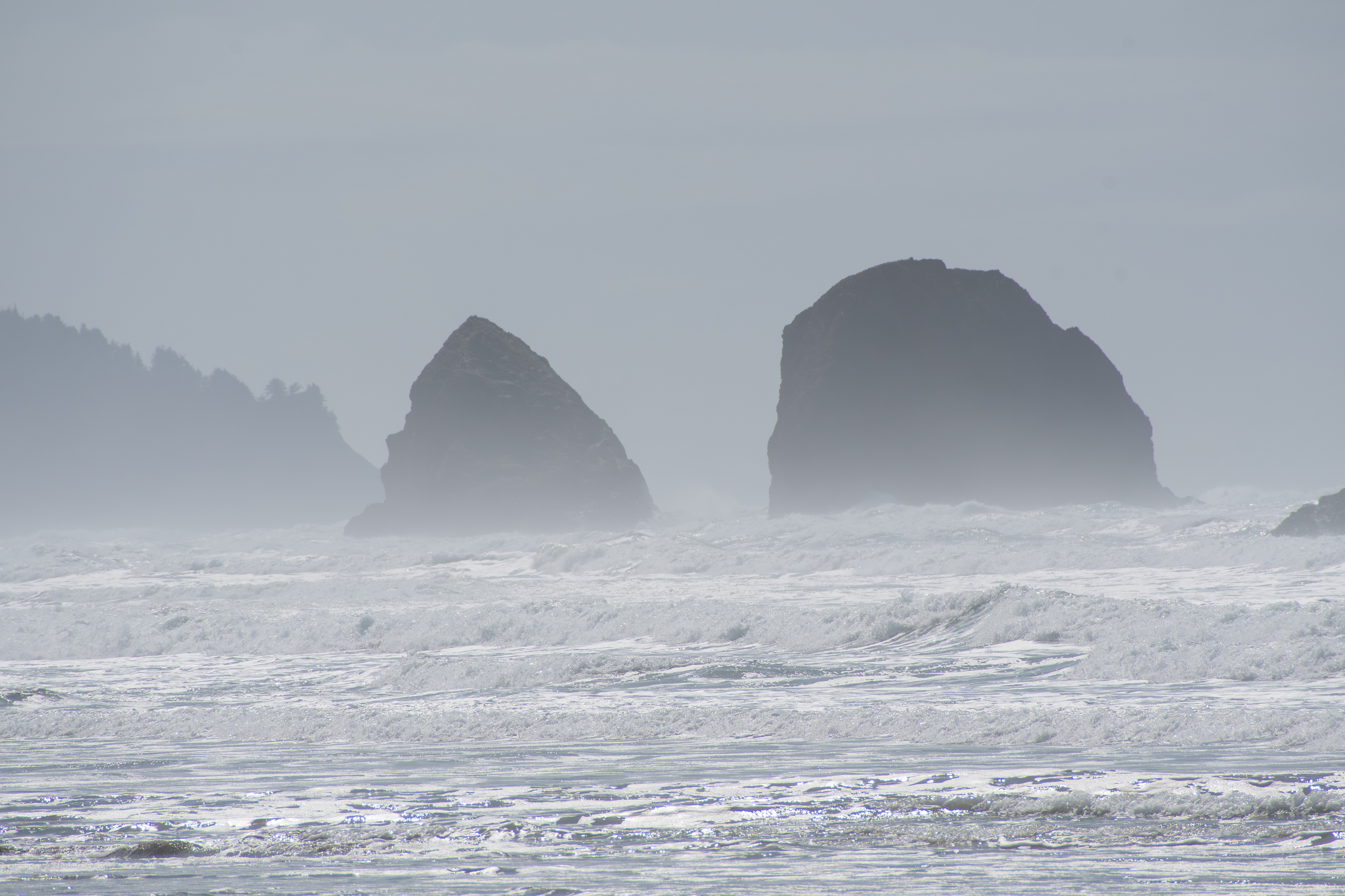 CANNON BEACH, OR, USA - APR 12, 2025: The iconic tall rock formations at Cannon Beach stand against the backdrop of a cloudy sky, creating a dramatic coastal scene along the Pacific Northwest shorelin