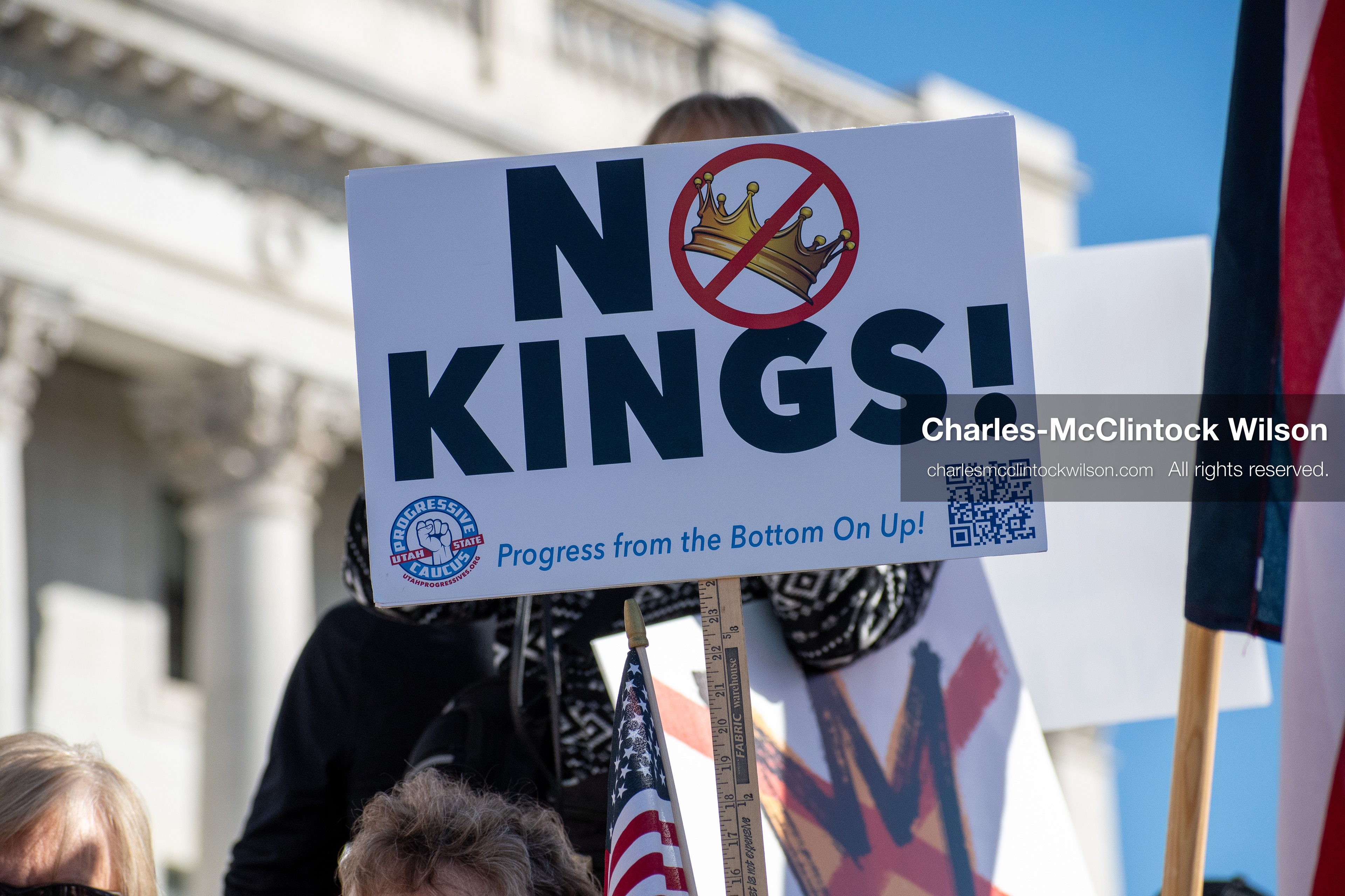 October 18, 2025, Salt Lake City, Utah, USA: A demonstrator raises a placard during a "No Kings" protest held at the Utah State Capitol. Other participants and signs are visible in the background during the public gathering.