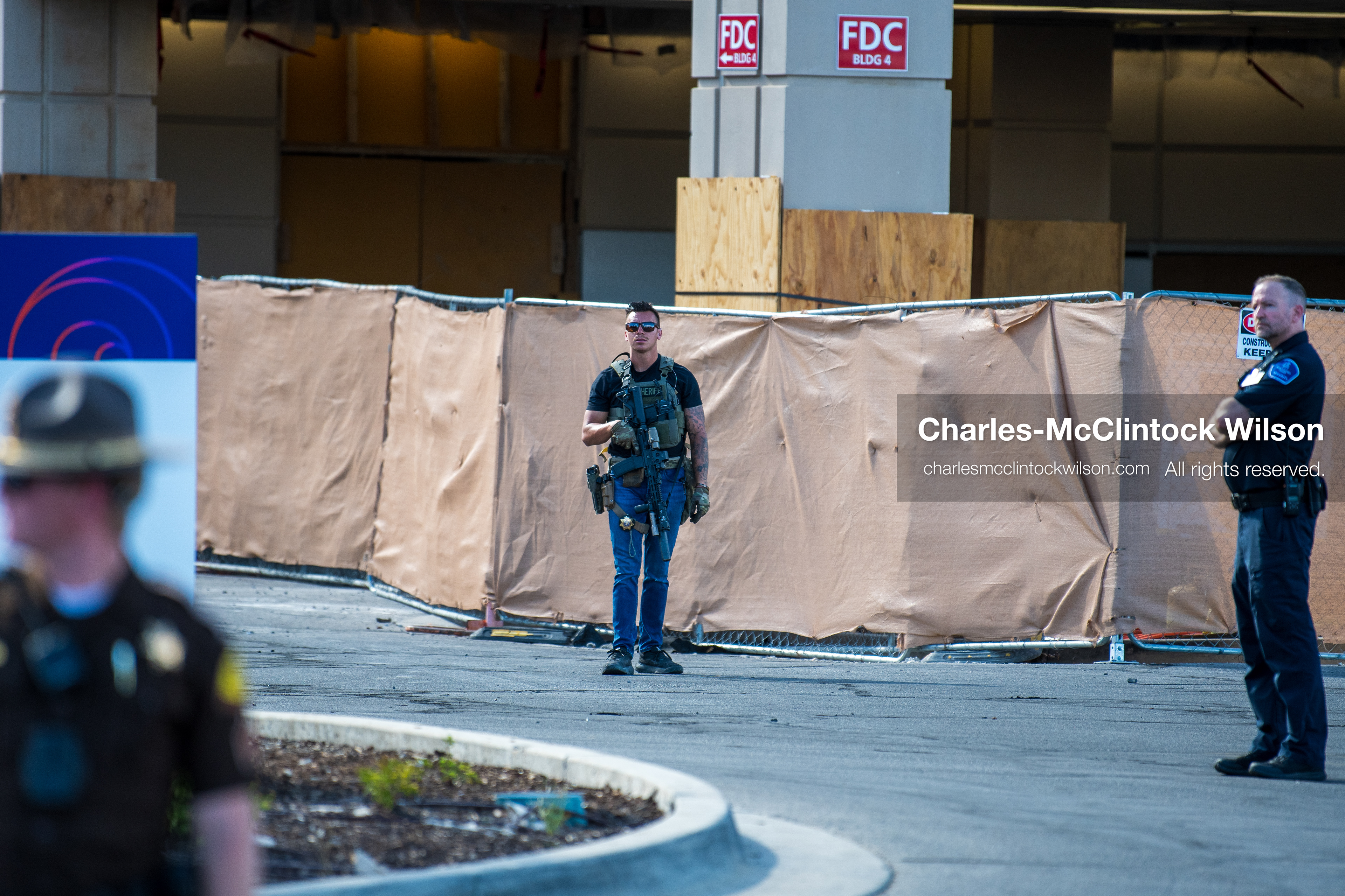 A local police officer stands near a temporary wall perimeter outside Intermountain Medical Center in Murray, Utah, United States, on August 17, 2026. Regional police agencies secured the hospital perimeter as a safety precaution after shooting victims were admitted following a fatal shootout outside a funeral service in nearby Kearns. (Photo by Charles-McClintock Wilson/NurPhoto)