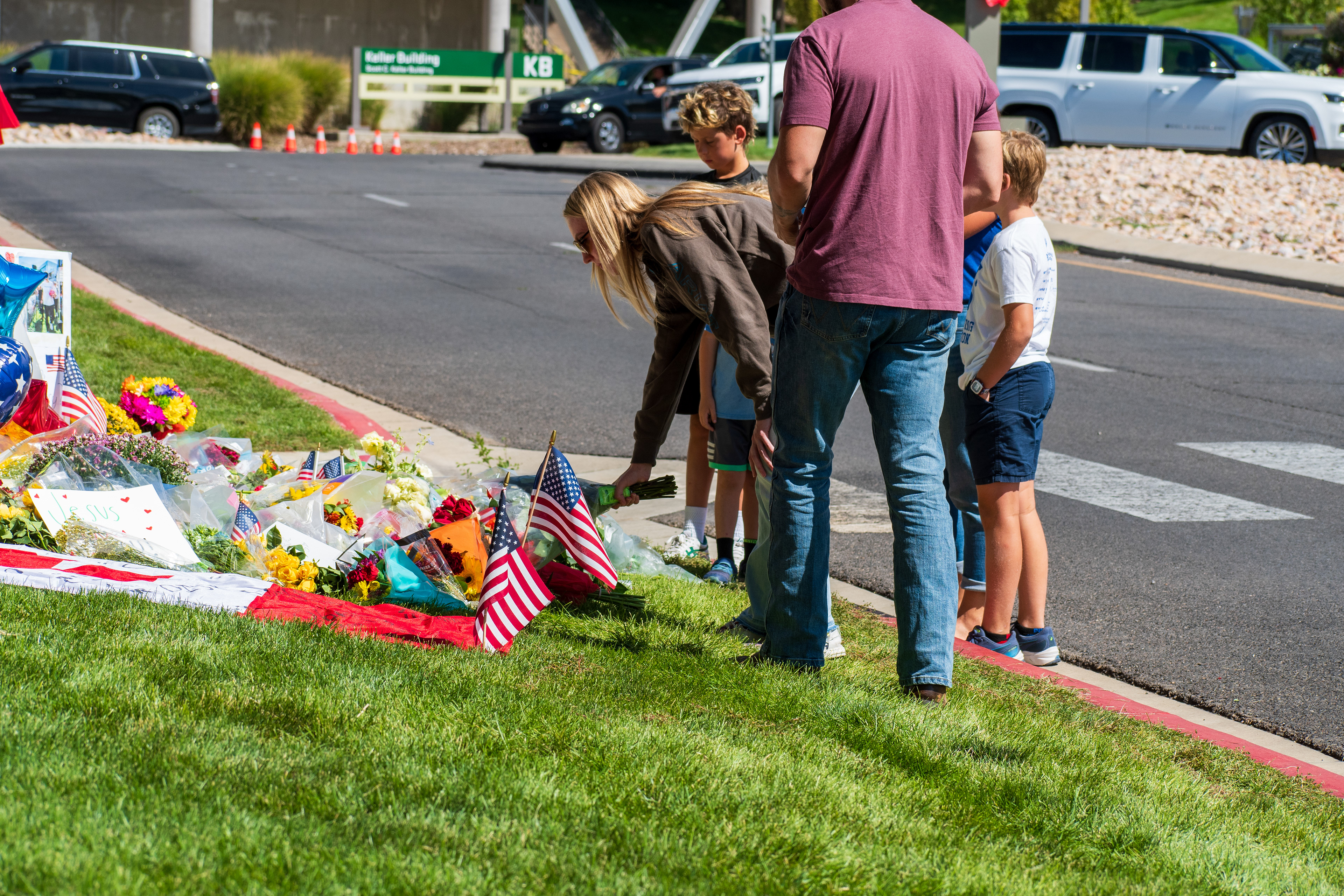 OREM, UTAH – SEPTEMBER 12, 2025: Families gather at a memorial site for Charlie Kirk on the campus of Utah Valley University. The tribute includes American flags, balloons, flowers, and handwritten posters arranged near a building entrance. © Charles‑McClintock Wilson / ZUMA Press