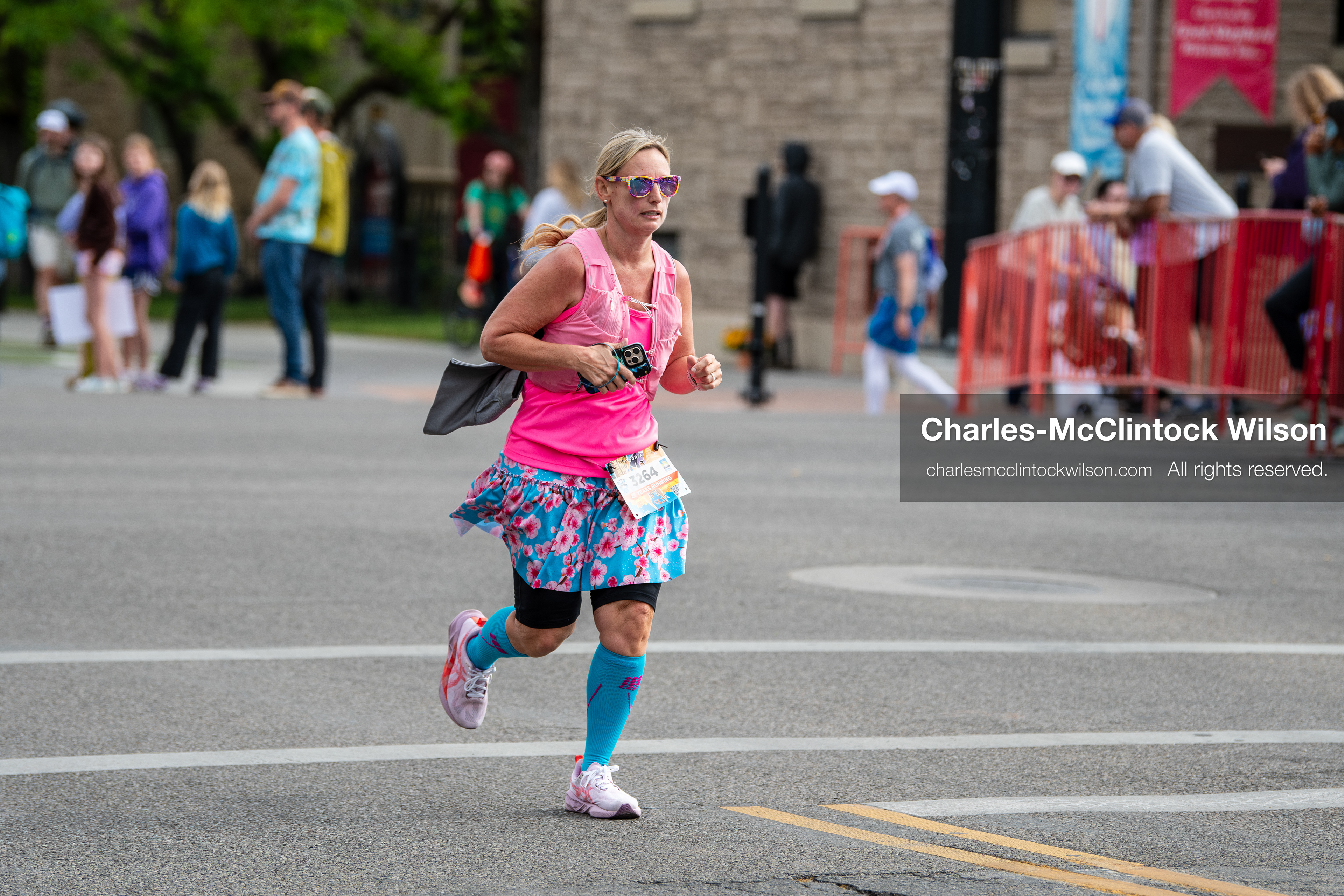 May 16, 2026, Ogden, Utah, USA: A runner wearing a bright pink top and patterned skirt competes in the 25th Annual America First Ogden Marathon in Ogden, Utah, on Saturday, May 16, 2026. Spectators line the course behind barricades as participants make their way through downtown streets during the milestone 25th running of the event. (Credit Image: © Charles-McClintock Wilson/ZUMA Press Wire)