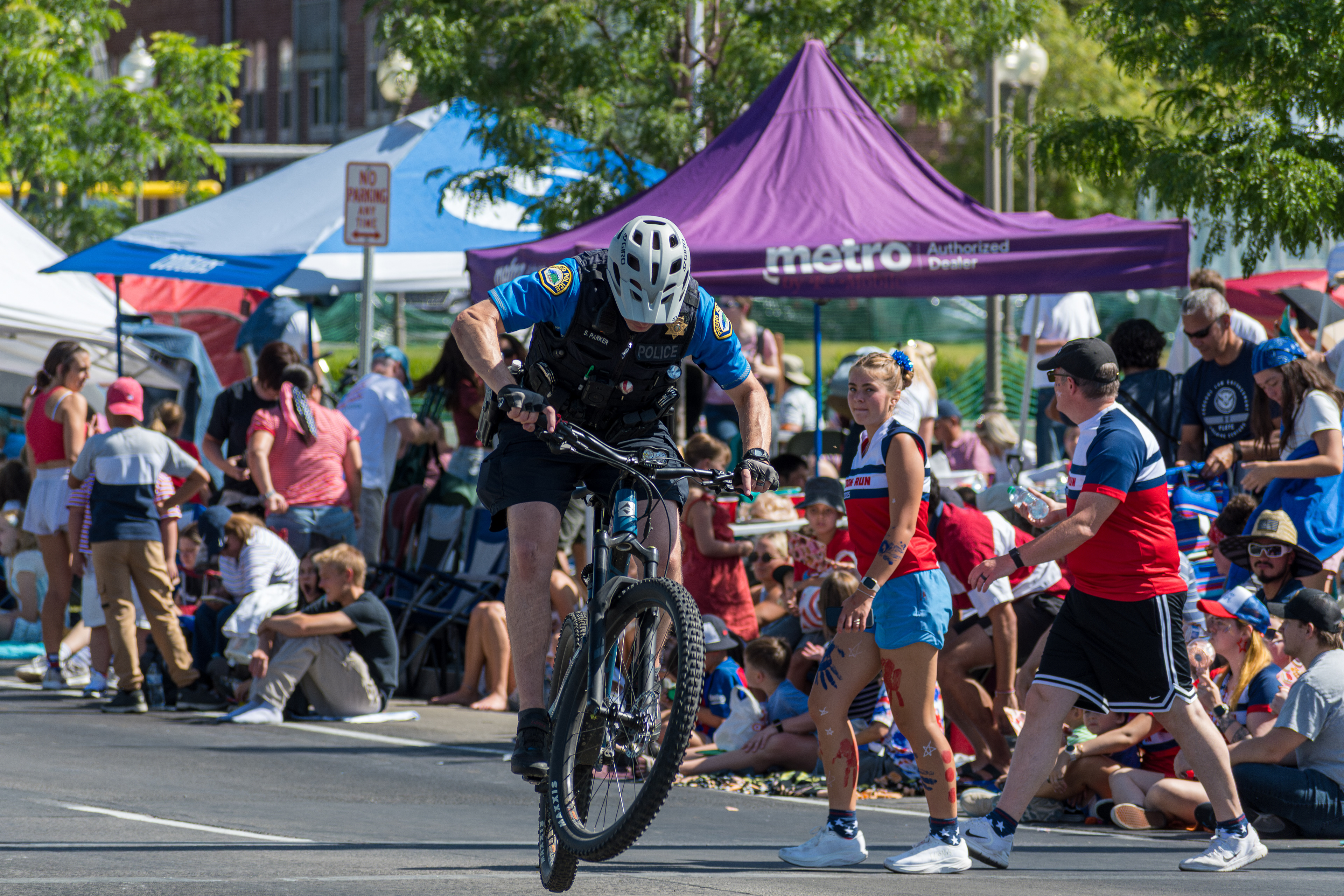 Provo, Utah – July 4, 2025: A police officer rides a bicycle along the parade route during the Freedom Festival Grand Parade, providing security and engaging with the community.