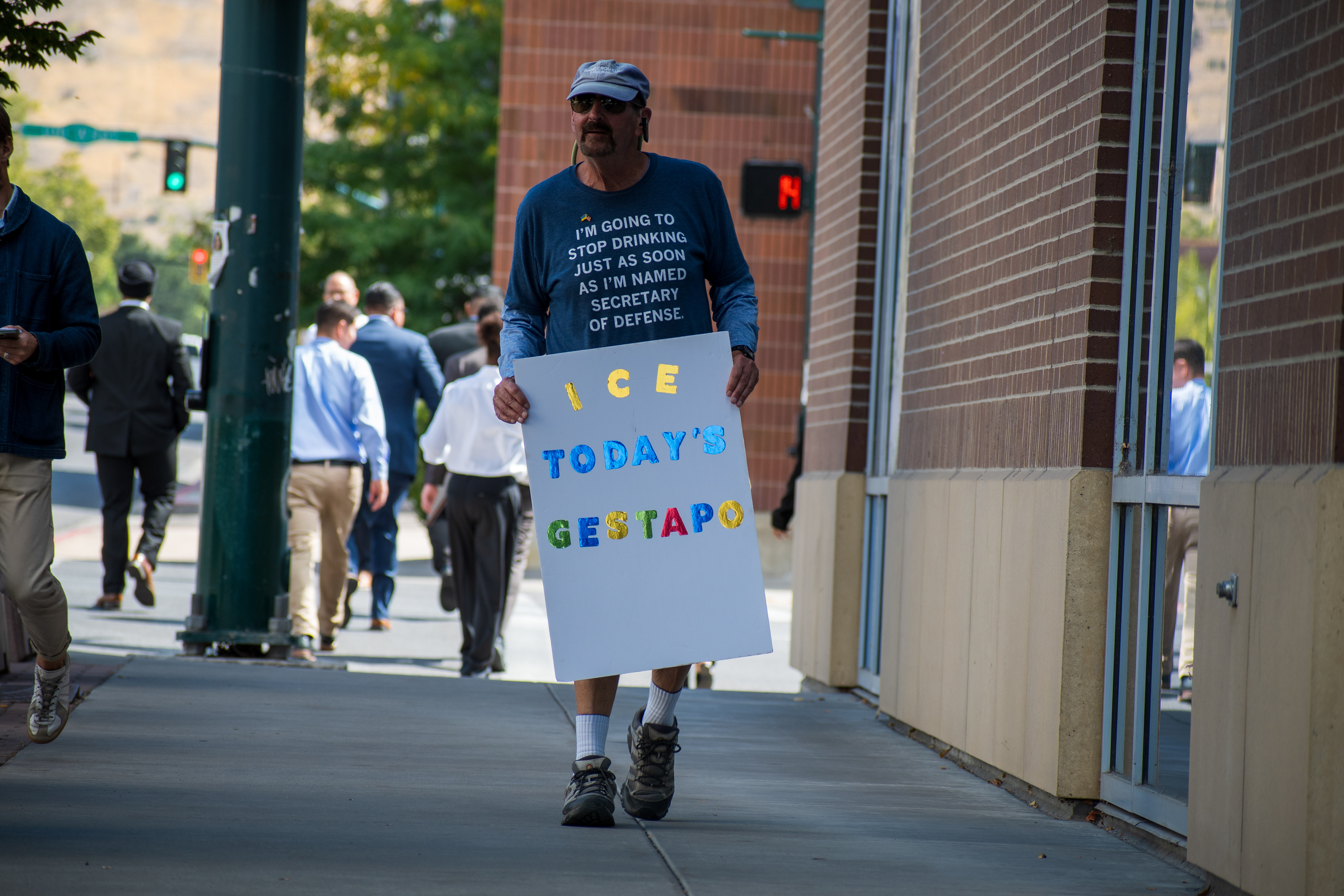 September 15, 2025 – Provo, Utah, United States: A demonstrator holds a sign reading “I C E TODAY’S GESTAPO” outside the Utah Valley Convention Center during a protest against the Department of Homeland Security career expo. The sign’s upper quote—“I’m going to stop drinking just as soon as I’m named Secretary of Defense”—adds satirical commentary on federal leadership and personal agency. Photograph by Charles‑McClintock Wilson / ZUMA Press Wire