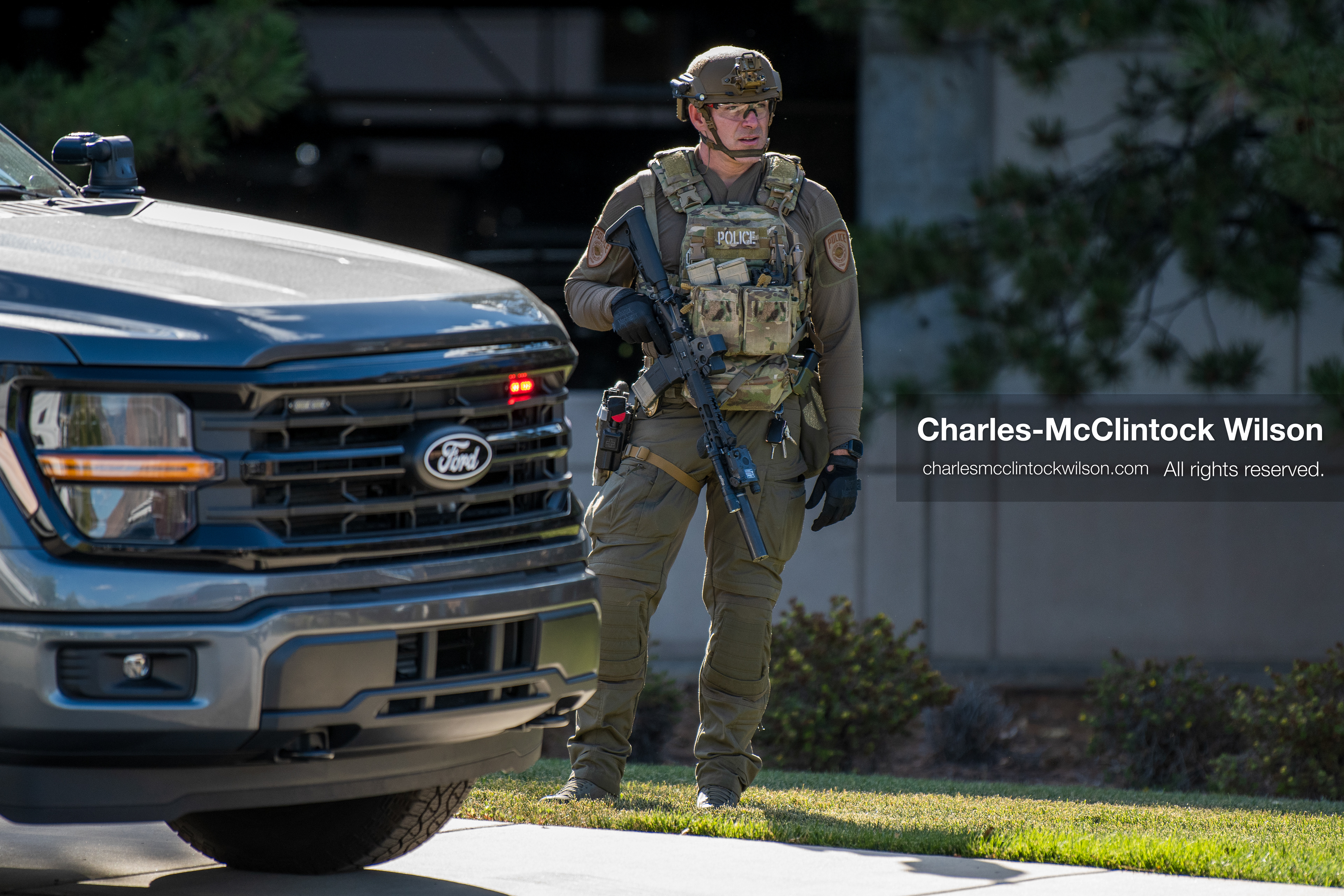An armed law enforcement officer wearing a helmet and tactical gear stands guard outside Intermountain Medical Center in Murray, Utah, United States, on August 17, 2026. Multiple regional police agencies secured the hospital perimeter as a safety precaution after shooting victims were admitted following a fatal shootout outside a funeral service in nearby Kearns. (Photo by Charles-McClintock Wilson/NurPhoto)