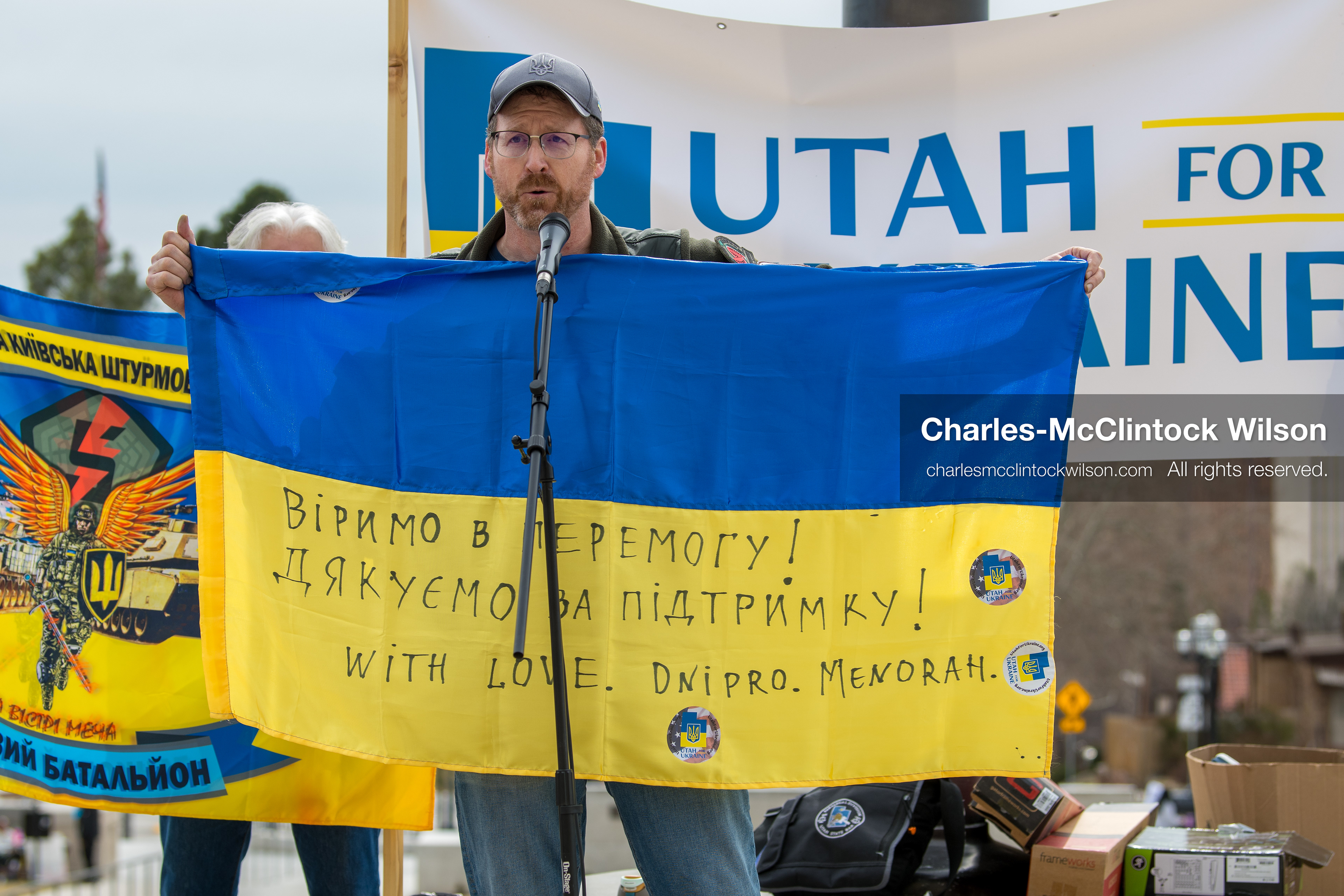 February 28, 2026, Salt Lake City, Utah, USA: NATHANIEL SANDERS, a Salt Lake County Deputy District Attorney and vocal advocate for Ukraine, holds a Ukrainian flag with messages of support while speaking during the Stand With Ukraine rally at the Utah State Capitol. The gathering marked the four year anniversary of the full scale Russian invasion of Ukraine and brought community members together in support of Ukrainians and local humanitarian efforts. (Credit Image: © Charles McClintock Wilson/ZUMA Press Wire)