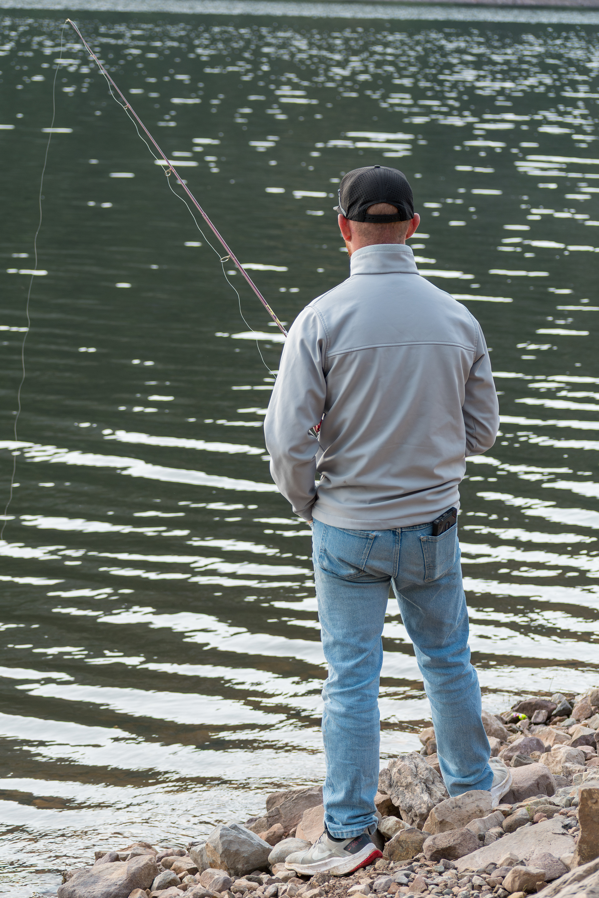 Summit County, Utah – July 20, 2025: A man fishes alone on the calm waters of Smith and Morehouse Reservoir during a quiet summer day.