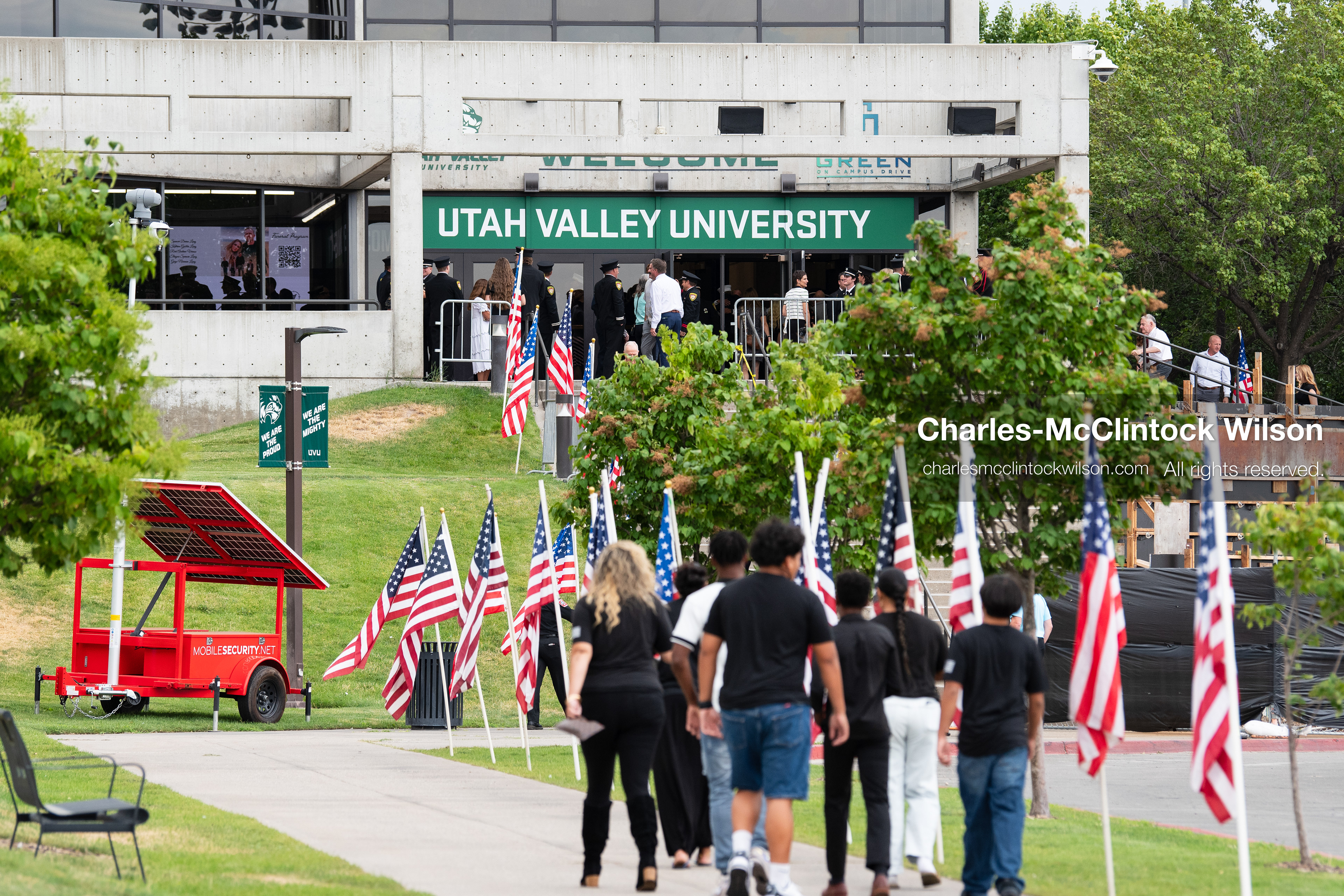 Attendees walk along a sidewalk lined with American flags toward the entrance of the UCCU Center on the campus of Utah Valley University in Orem, Utah, on Wednesday, July 29, 2026. More than 300 people came to the public memorial ceremony to honor Provo Fire Captain Spencer Long, his wife Katrina, and three of their sons, who died after a flash flood hit their campsite near the Sunglow Campground in Wayne County. (Photo by Charles-McClintock Wilson/Sipa USA)