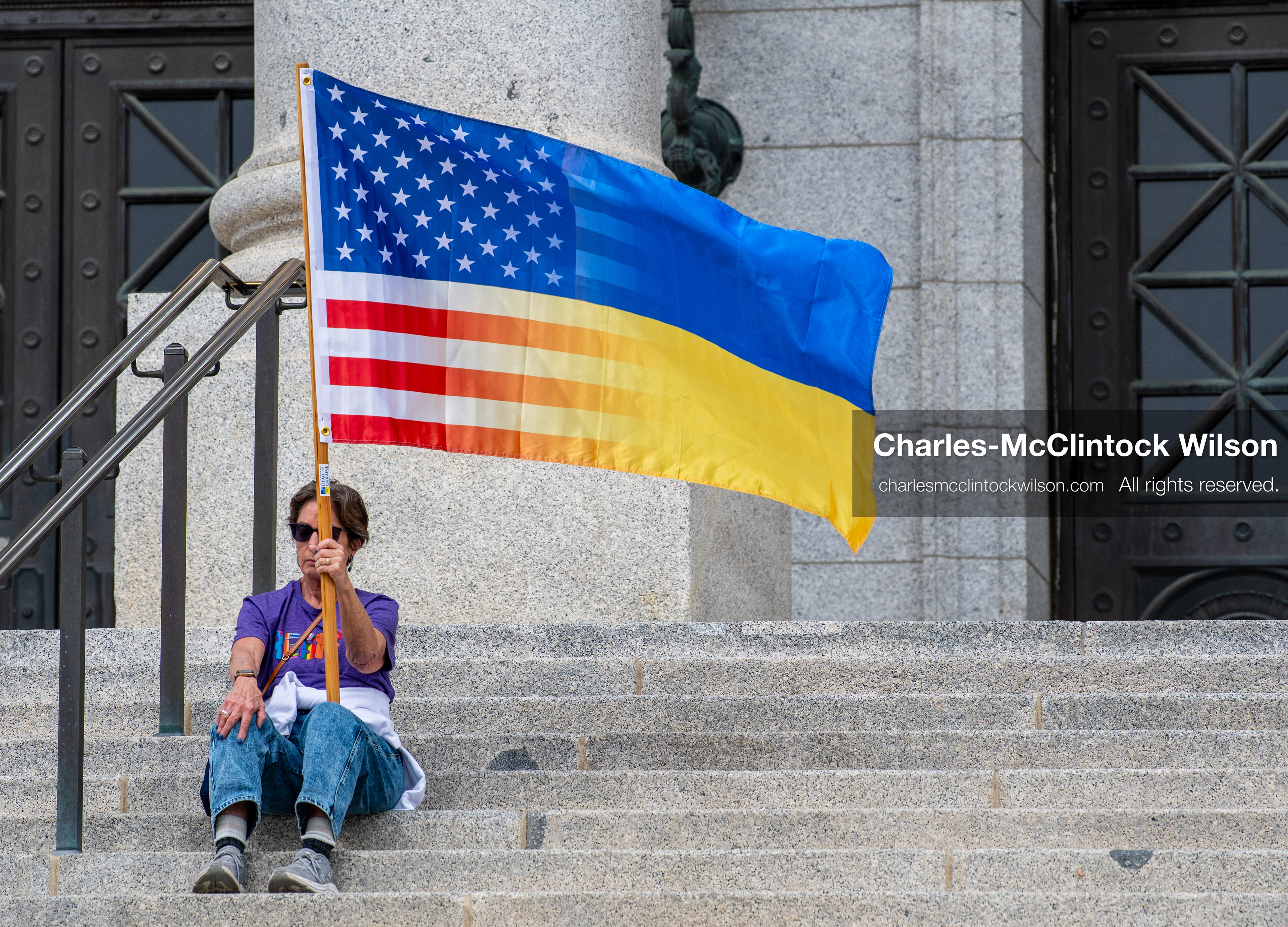February 28, 2026, Salt Lake City, Utah, USA: A demonstrator sits on the steps near the Utah State Capitol holding a hybrid United States and Ukrainian flag during the Stand With Ukraine rally. The gathering marked the four year anniversary of the full scale Russian invasion of Ukraine and brought community members together in support of Ukrainians and local humanitarian efforts. (Credit Image: © Charles McClintock Wilson/ZUMA Press Wire)