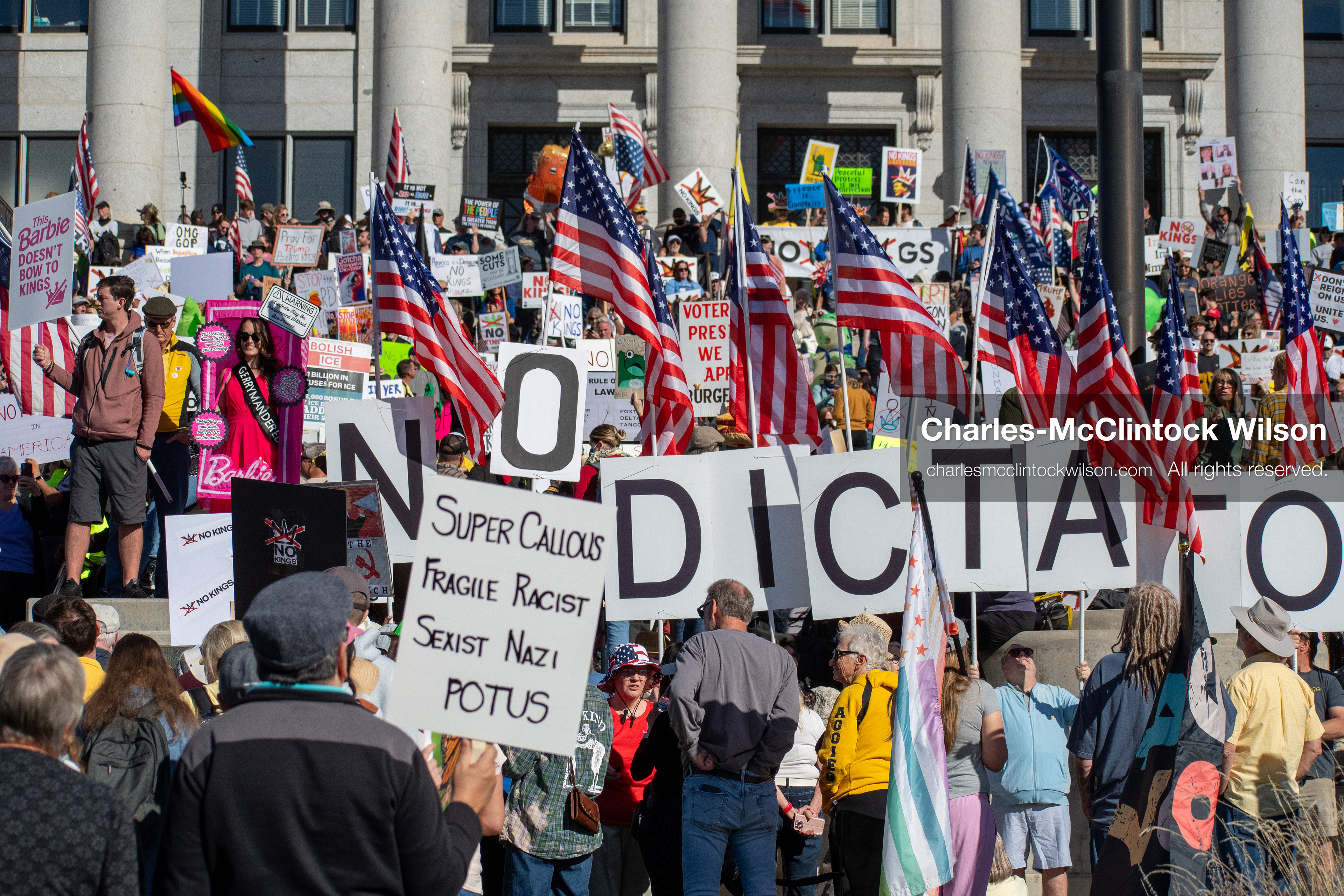 October 18, 2025, Salt Lake City, Utah, USA: Demonstrators gather on the steps of the Utah State Capitol during a "No Kings" protest held as part of a nationwide mobilization. Participants hold signs and flags while documenting the event. The protest was one of several organized across the United States.