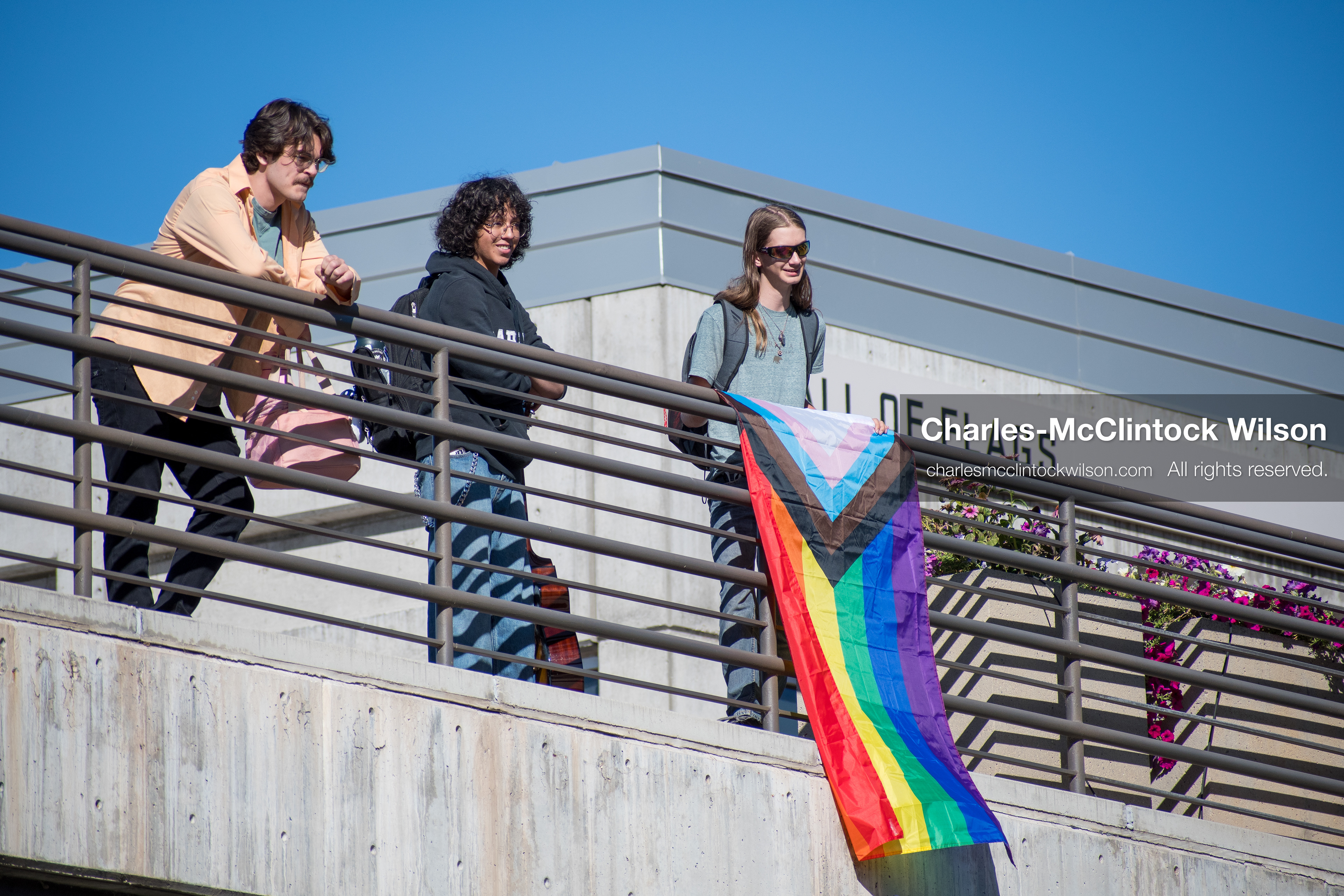 September 10, 2025, Orem, Utah, USA: A group of individuals stand atop the Fountain Courtyard at Utah Valley University, holding a Progress Pride flag during conservative activist Charlie Kirk’s American Comeback Tour appearance. The event drew over 3,000 attendees and was marked by heightened civic tension and symbolic gestures from both supporters and critics. Kirk was fatally shot moments later during the public Q&A session, prompting national scrutiny of campus security protocols and institutional response. (Credit Image: © Charles‑McClintock Wilson/ZUMA Press Wire)