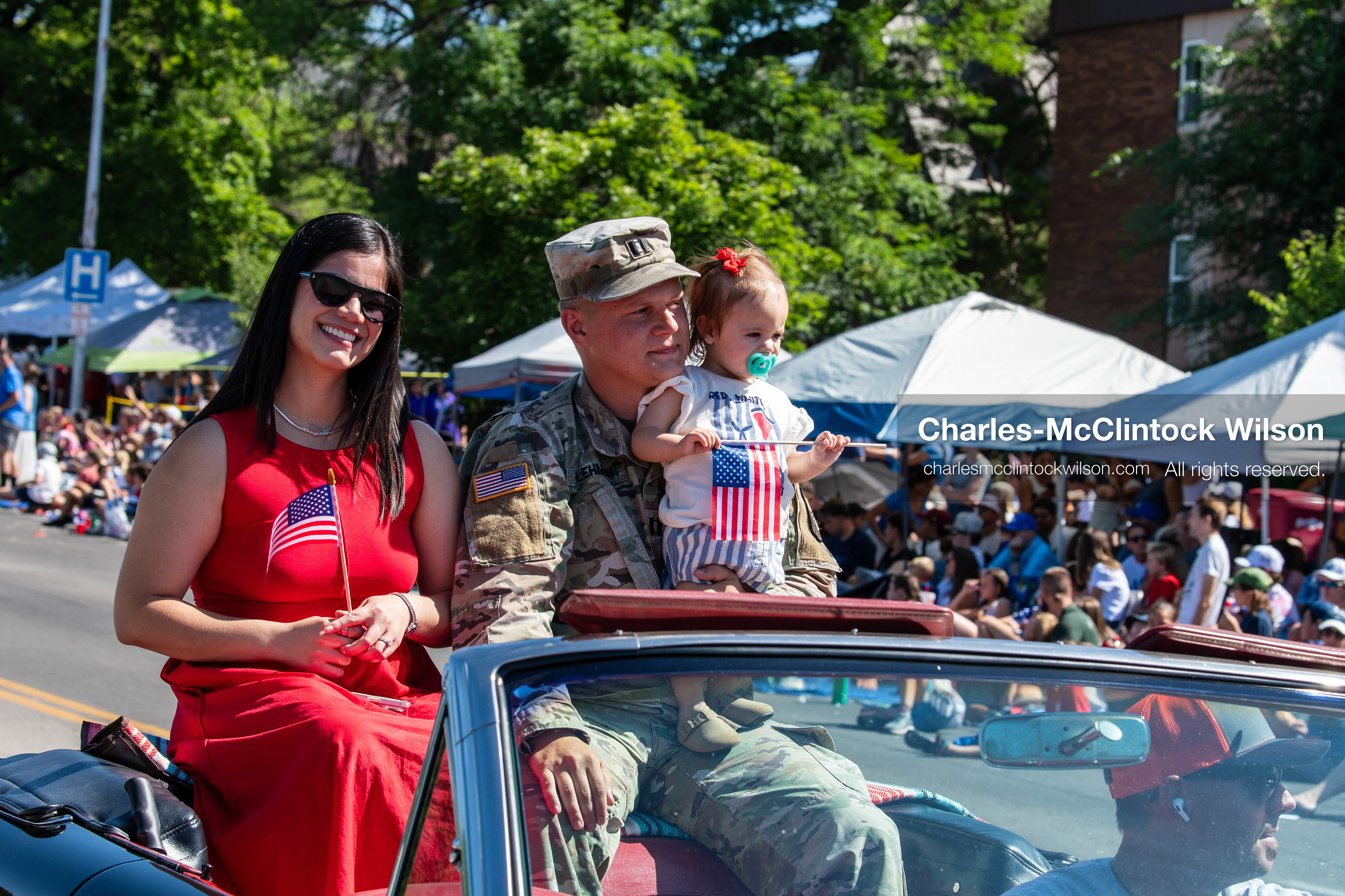 July 4, 2026, Provo, Utah, USA: A military service member in uniform holds a child beside a woman in a red dress as they ride in a convertible during America's Freedom Festival Grand Parade in Provo, Utah, Saturday, July 4, 2026. The annual Independence Day event features expanded programming to honor the 250th anniversary of United States independence. (Credit Image: © Charles-McClintock Wilson/ZUMA Press Wire)
