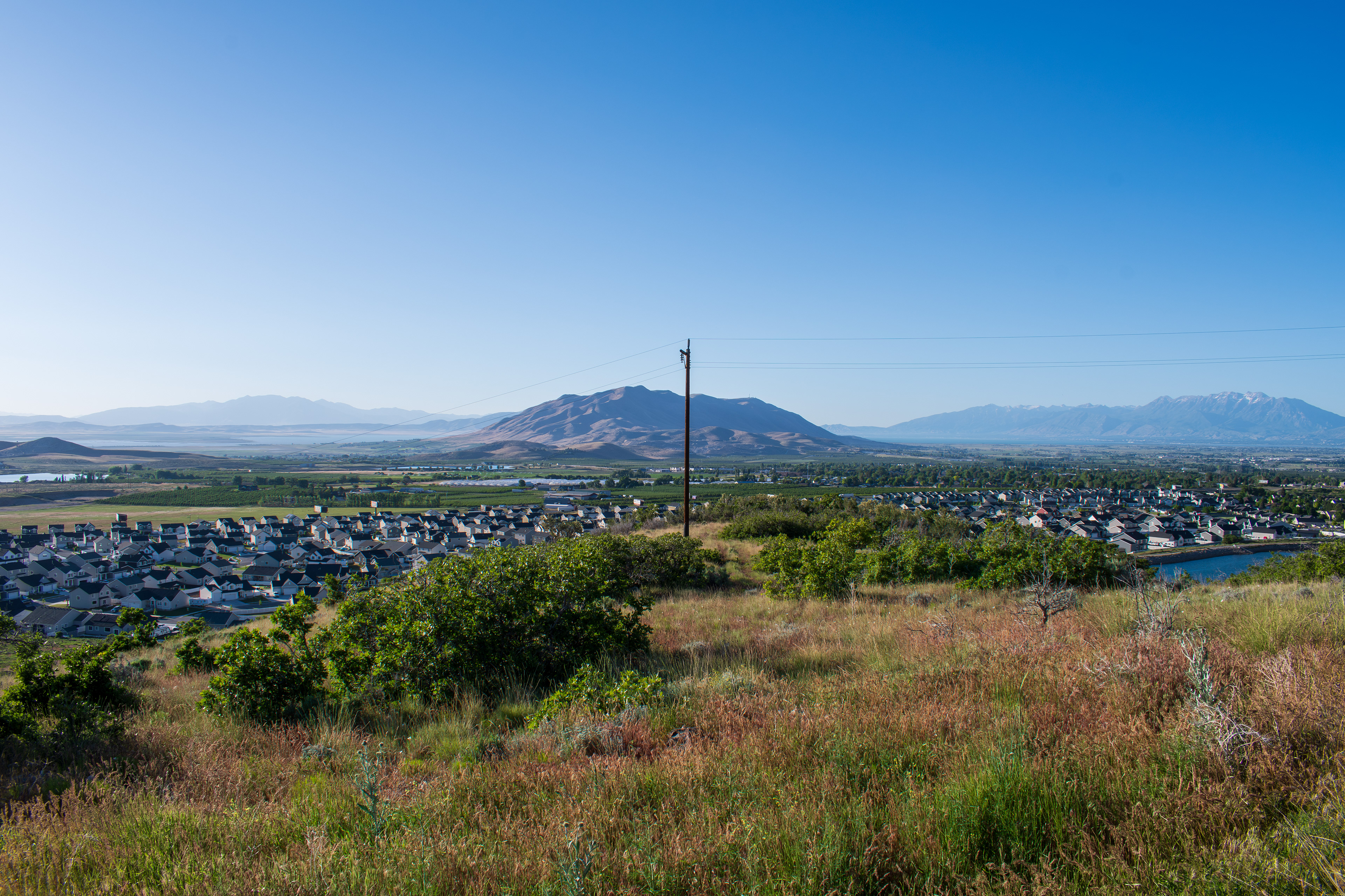 Santaquin, Utah – June 2, 2025: Wide view of a residential neighborhood with a mountainous backdrop and open valley under a clear sky.