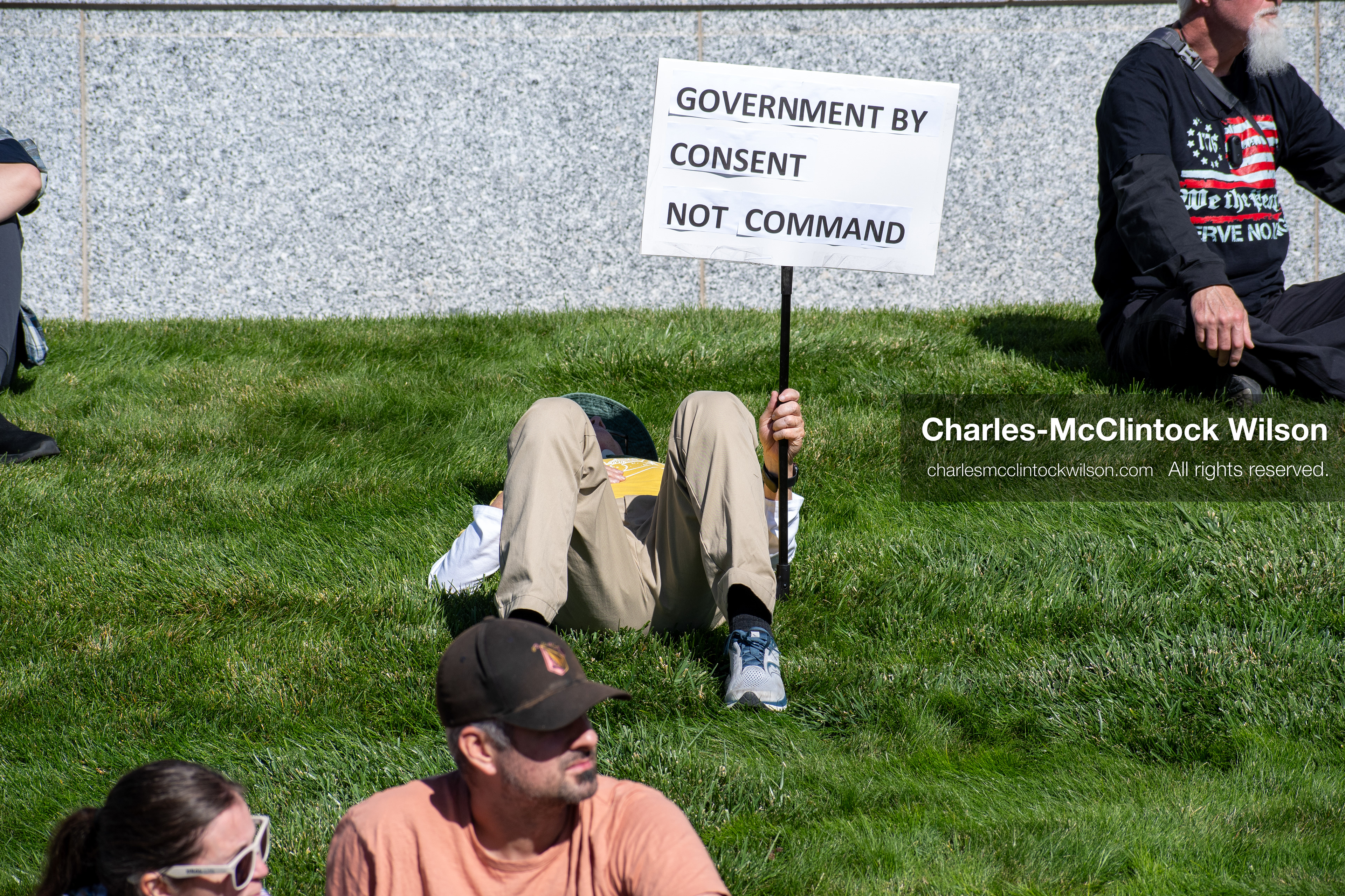 October 18, 2025, Salt Lake City, Utah, USA: A demonstrator raises a placard during a "No Kings" protest held at the Utah State Capitol. Other participants and signs are visible in the background during the public gathering.