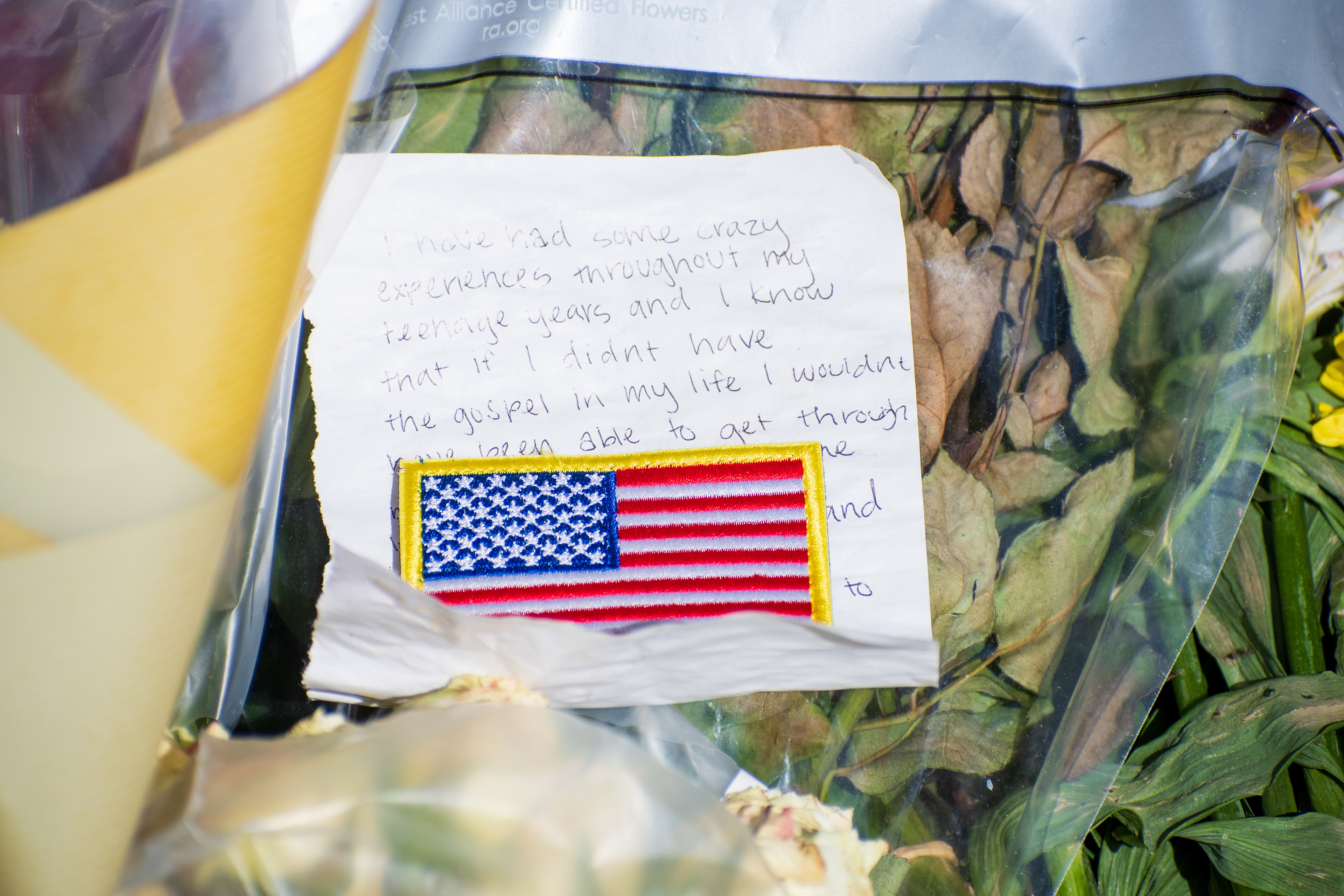 OREM, UTAH – SEPTEMBER 15, 2025: A handwritten note with an American flag patch is placed among dried and fresh flowers at a memorial site for Charlie Kirk on the campus of Utah Valley University. The note references personal experiences and religious faith. © Charles‑McClintock Wilson / ZUMA Press
