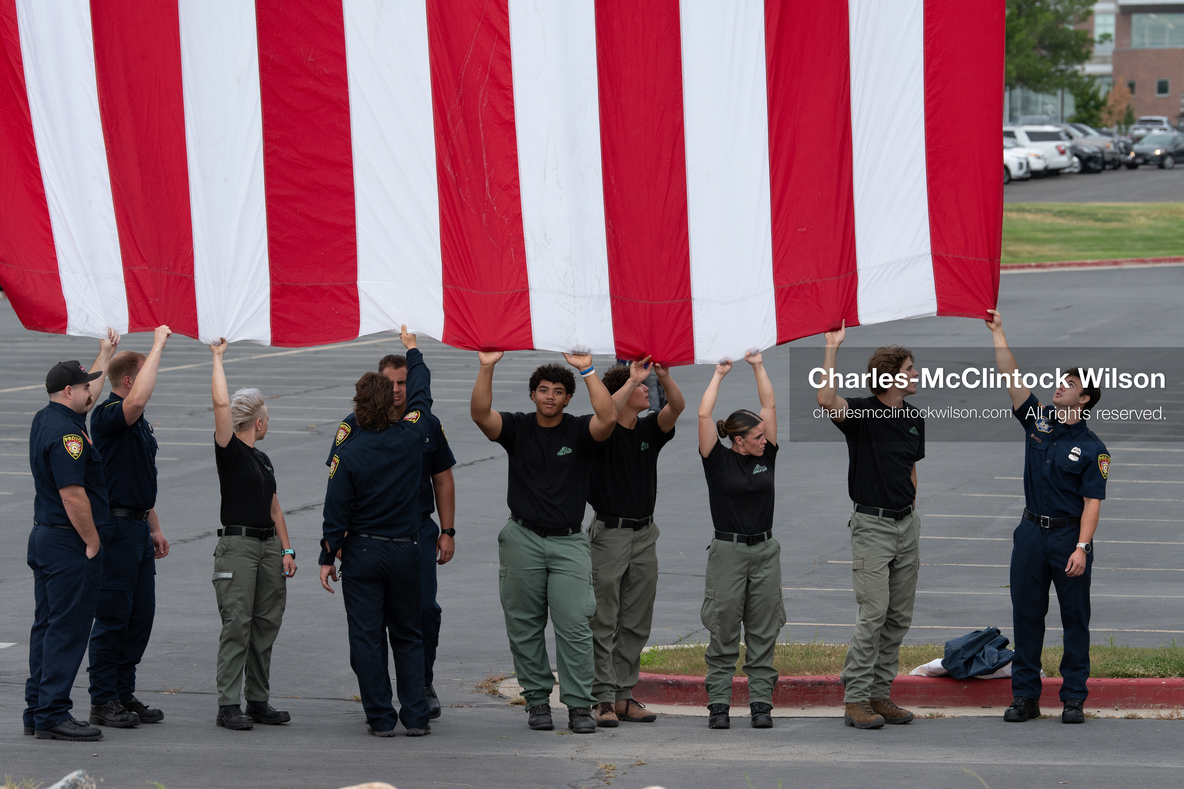 First responders stand in a row holding the bottom edge of a large American flag outside the UCCU Center at Utah Valley University in Orem, Utah, on Wednesday, July 29, 2026. More than 300 people came to the public memorial ceremony to honor Provo Fire Captain Spencer Long, his wife Katrina, and three of their sons, who died after a flash flood hit their campsite near the Sunglow Campground in Wayne County. (Photo by Charles-McClintock Wilson/Sipa USA)
