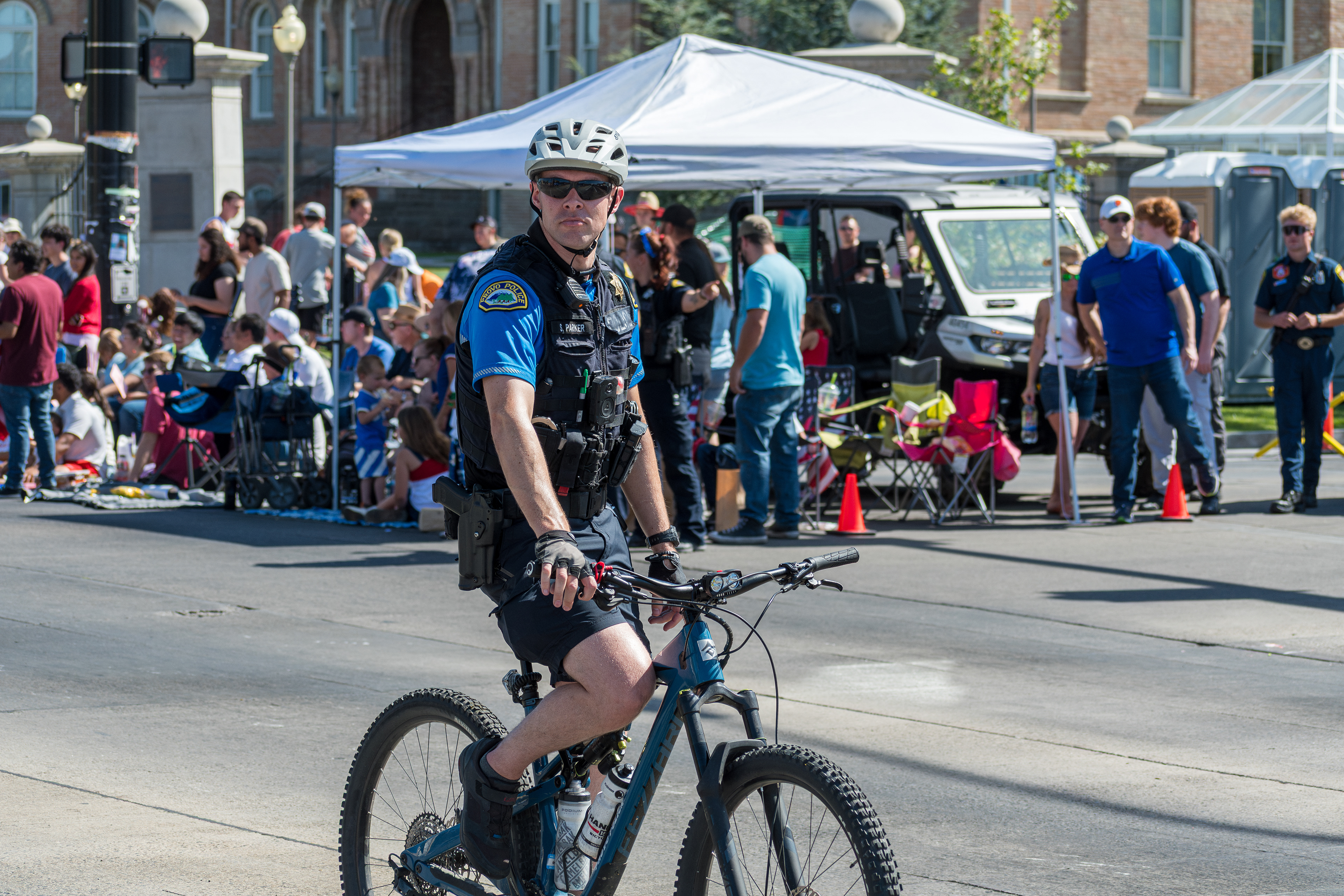 Provo, Utah – July 4, 2025: A police officer rides a bicycle along the parade route during the Freedom Festival Grand Parade, providing security and engaging with the community.