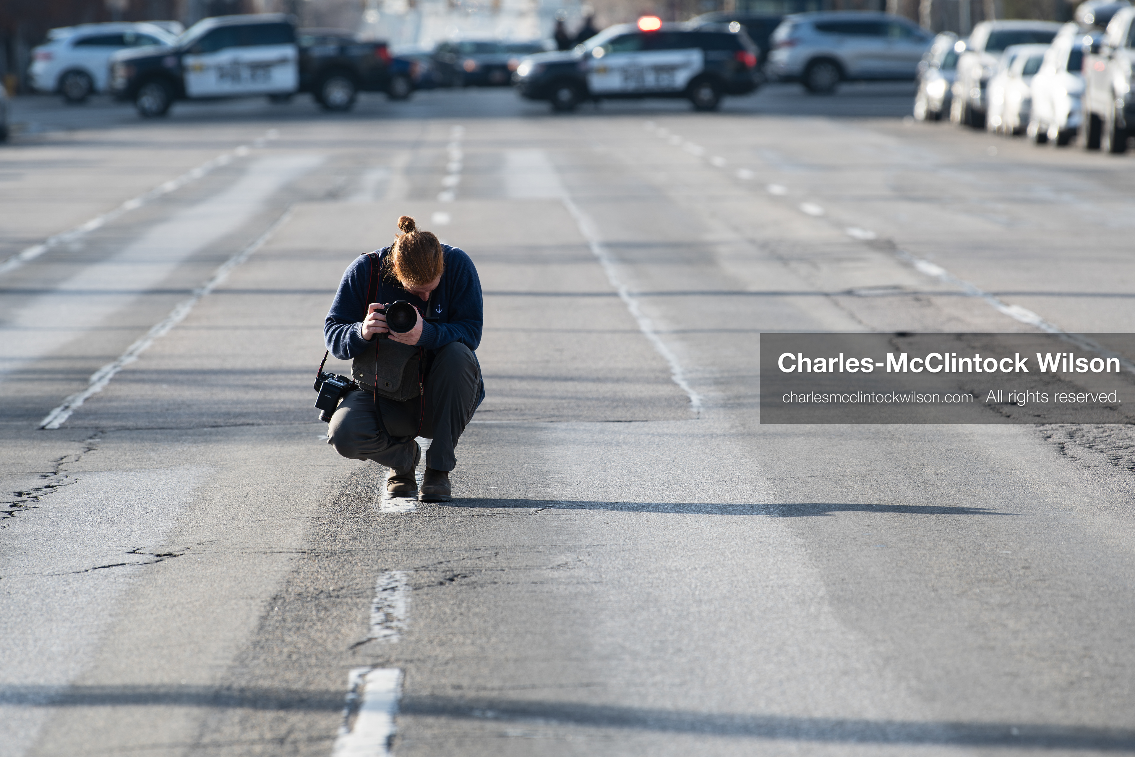 January 30, 2026, Salt Lake City, Utah, USA: A photographer crouches in the street as police vehicles block traffic during an anti‑ICE protest in Salt Lake City, part of a nationwide response to immigration enforcement policies. (Credit Image: © Charles‑McClintock Wilson/ZUMA Press Wire)
