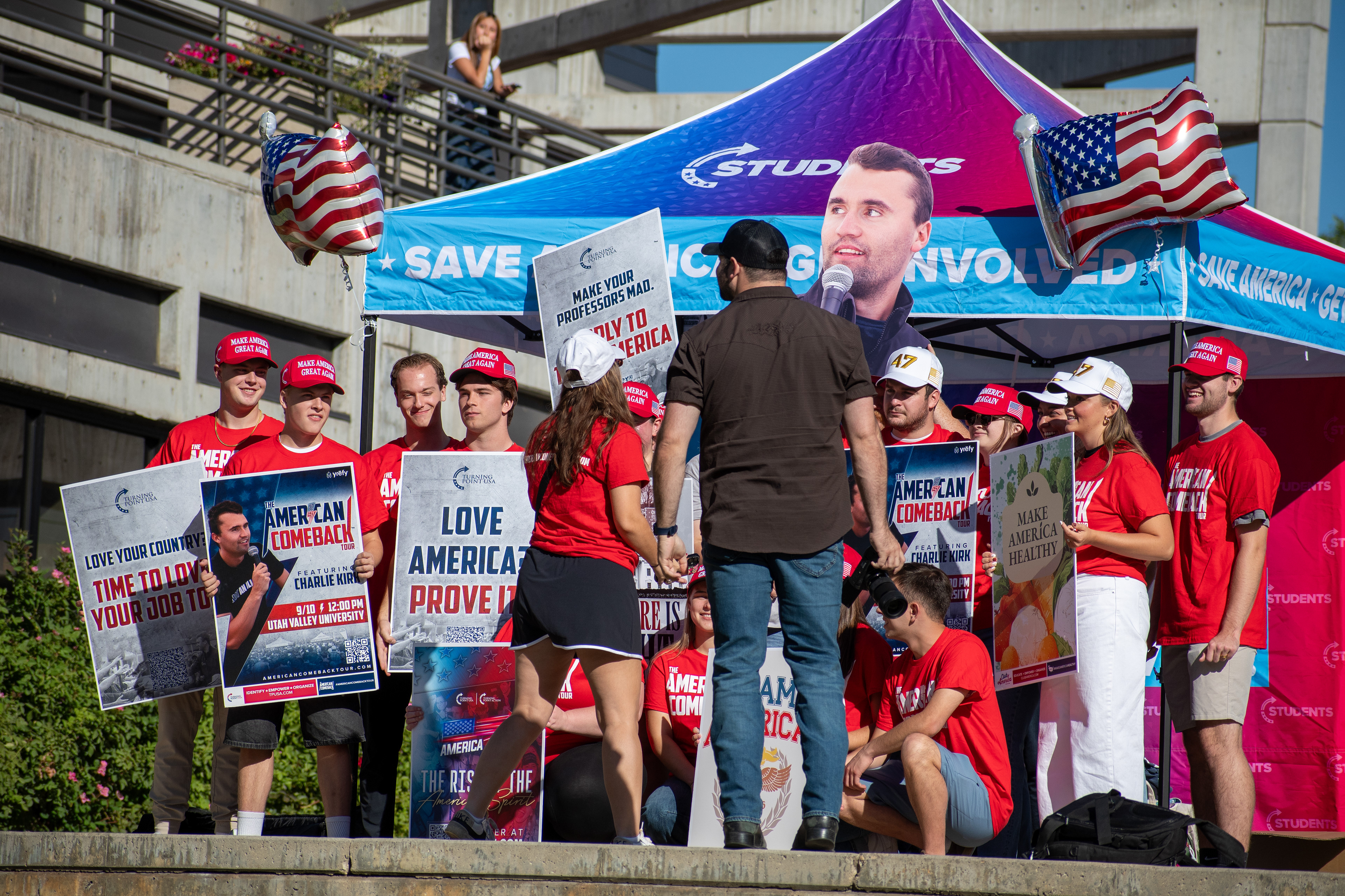 OREM, UTAH – SEPTEMBER 10, 2025: Attendees gather outside the Pope Science building at Utah Valley University during the opening stop of the American Comeback Tour. Surrounded by signage and coordinated attire, the group reflects a moment of thematic clarity, civic invitation, and communal energy. The image captures the rhythm of participation and the visual texture that shaped the event’s atmosphere. © Charles-McClintock Wilson / ZUMA Press