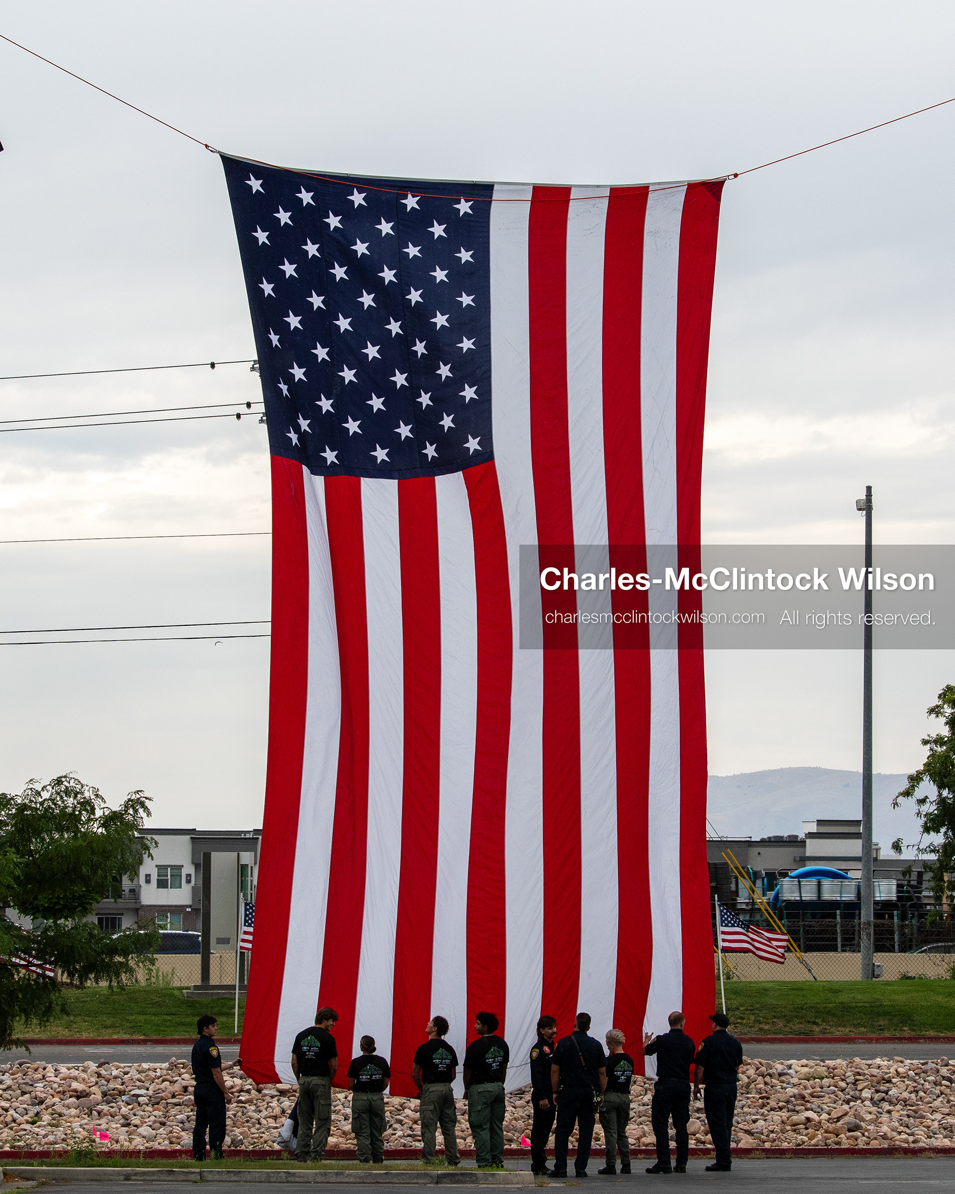 A group of first responders hangs a large American flag vertically outside the UCCU Center at Utah Valley University in Orem, Utah, on Wednesday, July 29, 2026. More than 300 people came to the public memorial ceremony to honor Provo Fire Captain Spencer Long, his wife Katrina, and three of their sons, who died after a flash flood hit their campsite near the Sunglow Campground in Wayne County. (Photo by Charles-McClintock Wilson/Sipa USA)