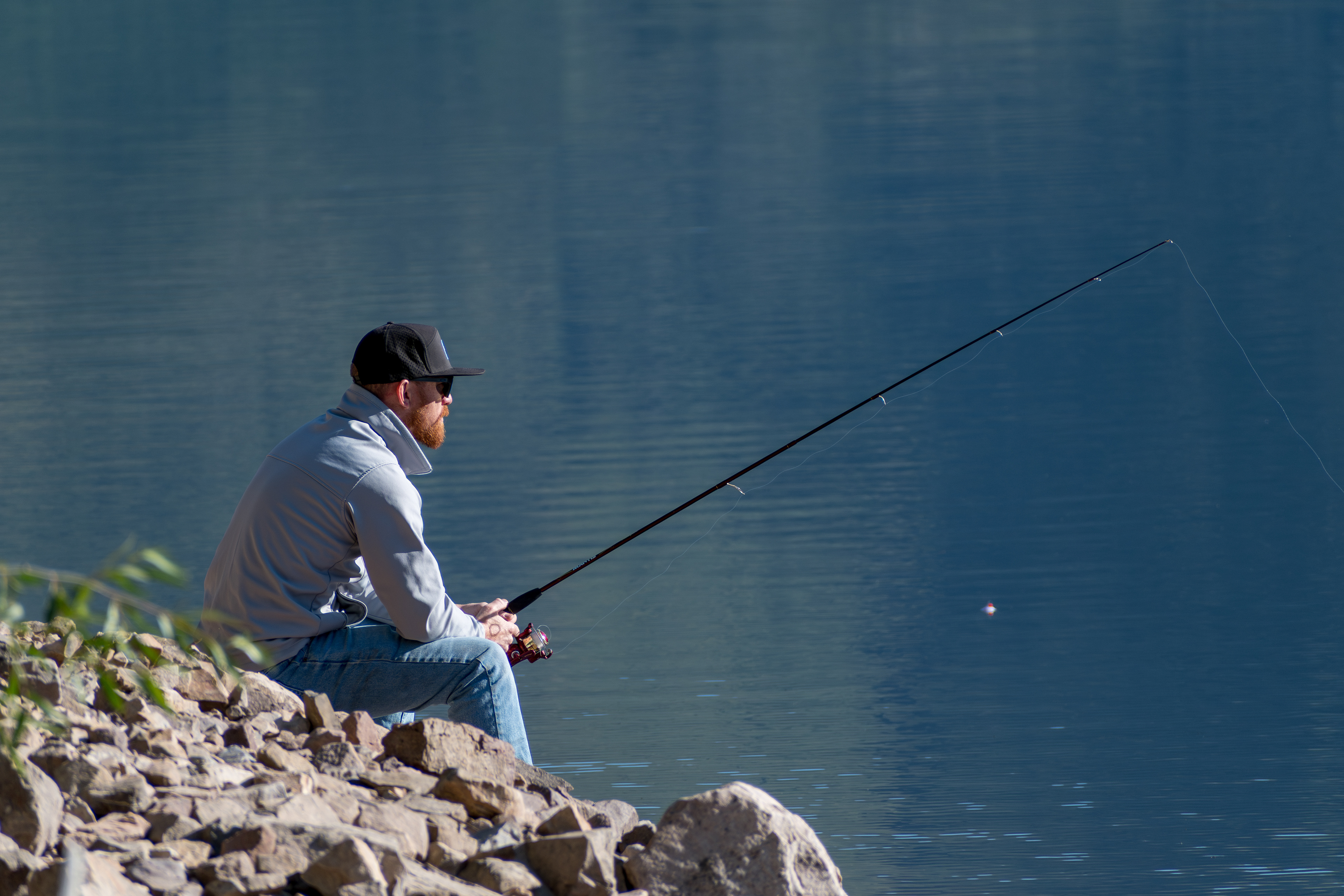 Summit County, Utah – July 20, 2025: A man fishes alone on the calm waters of Smith and Morehouse Reservoir during a quiet summer day.