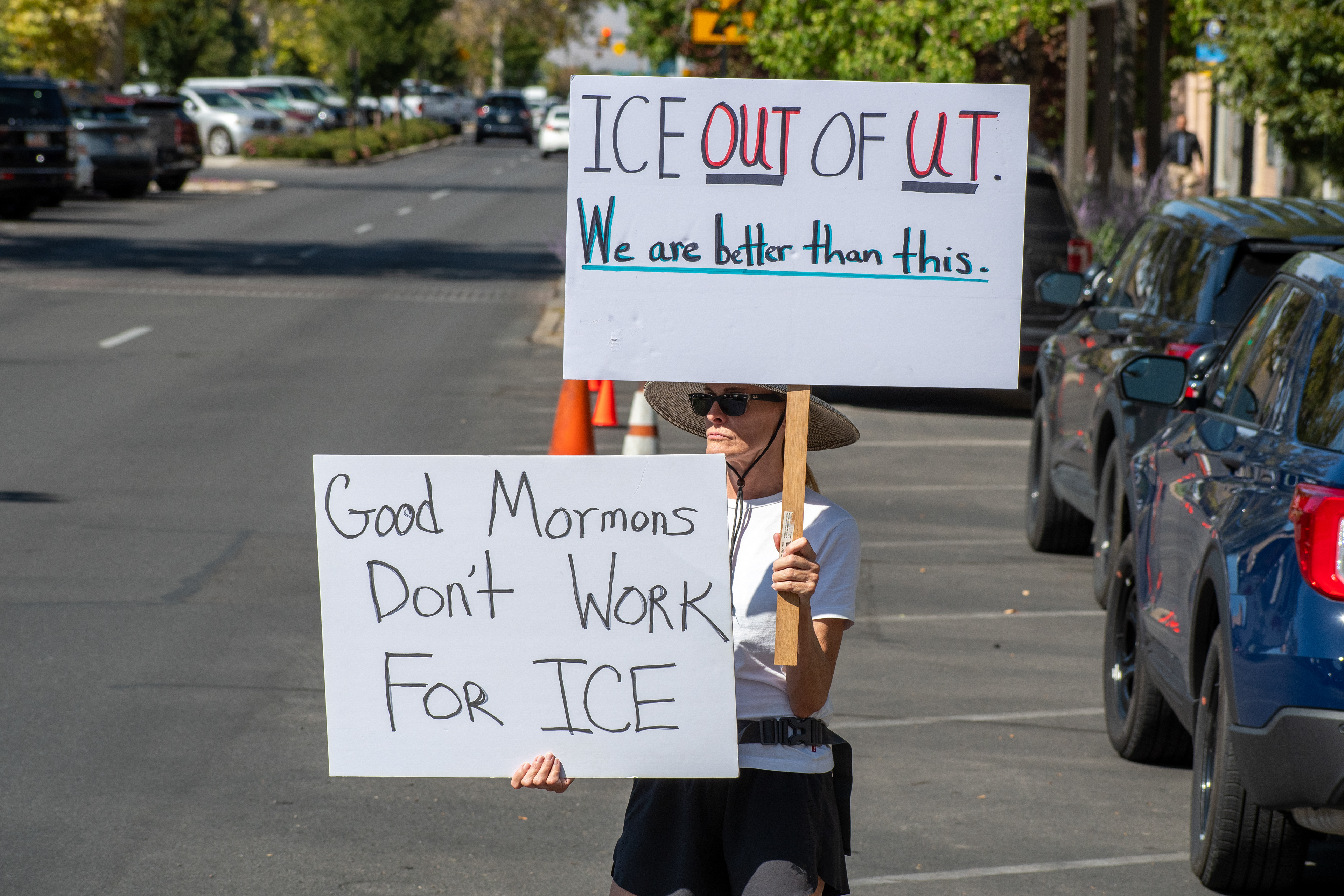 September 15, 2025 – Provo, Utah, United States: A demonstrator holds two signs outside the Utah Valley Convention Center during a protest against the Department of Homeland Security career expo. One sign reads “ICE OUT OF UT. We are better than this,” while the other declares “Good Mormons Don’t Work FOR ICE,” invoking regional identity and ethical critique. Photograph by Charles‑McClintock Wilson / ZUMA Press Wire