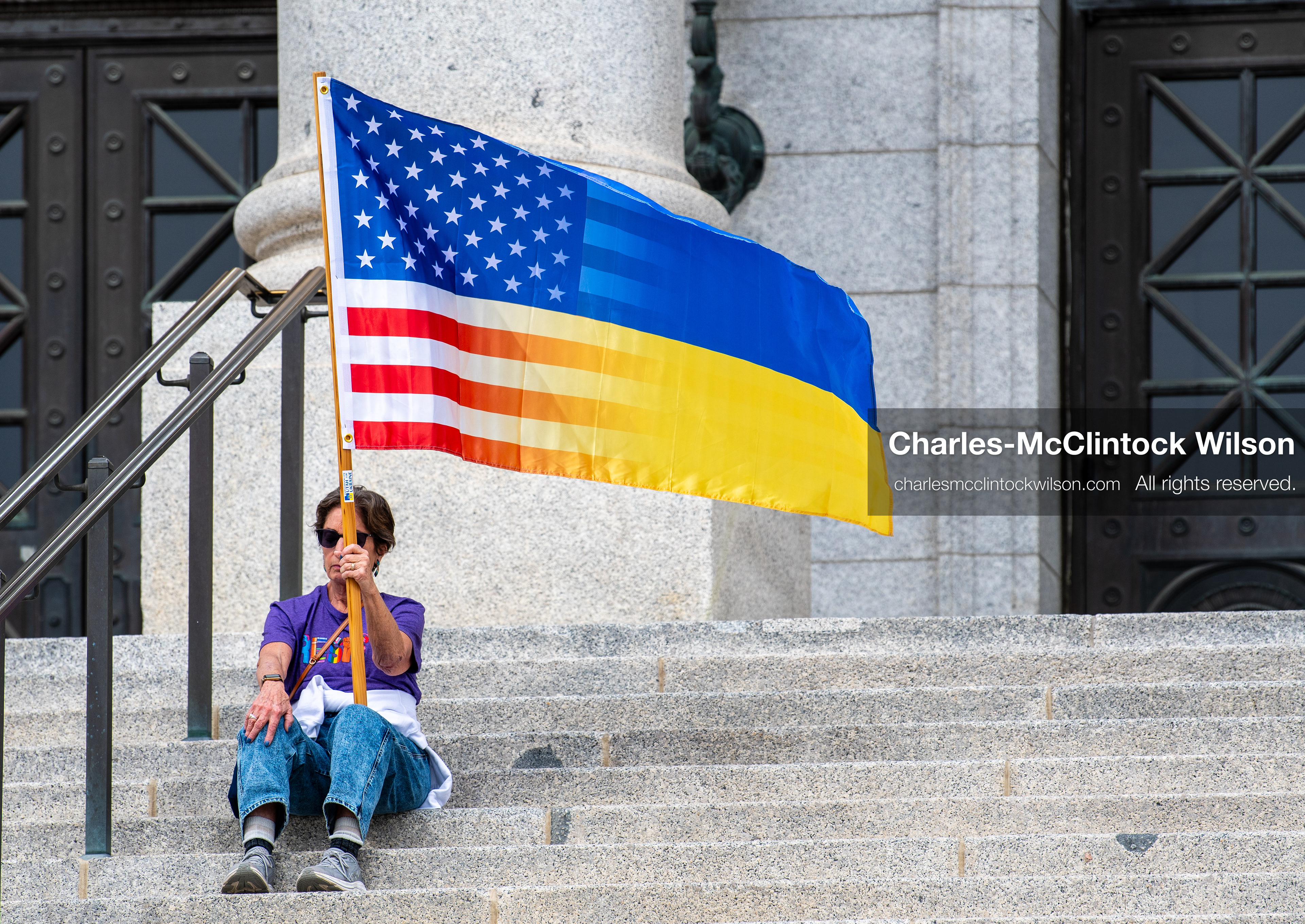 February 28, 2026, Salt Lake City, Utah, USA: A demonstrator sits on the steps near the Utah State Capitol holding a hybrid United States and Ukrainian flag during the Stand With Ukraine rally. The gathering marked the four year anniversary of the full scale Russian invasion of Ukraine and brought community members together in support of Ukrainians and local humanitarian efforts. (Credit Image: © Charles McClintock Wilson/ZUMA Press Wire)