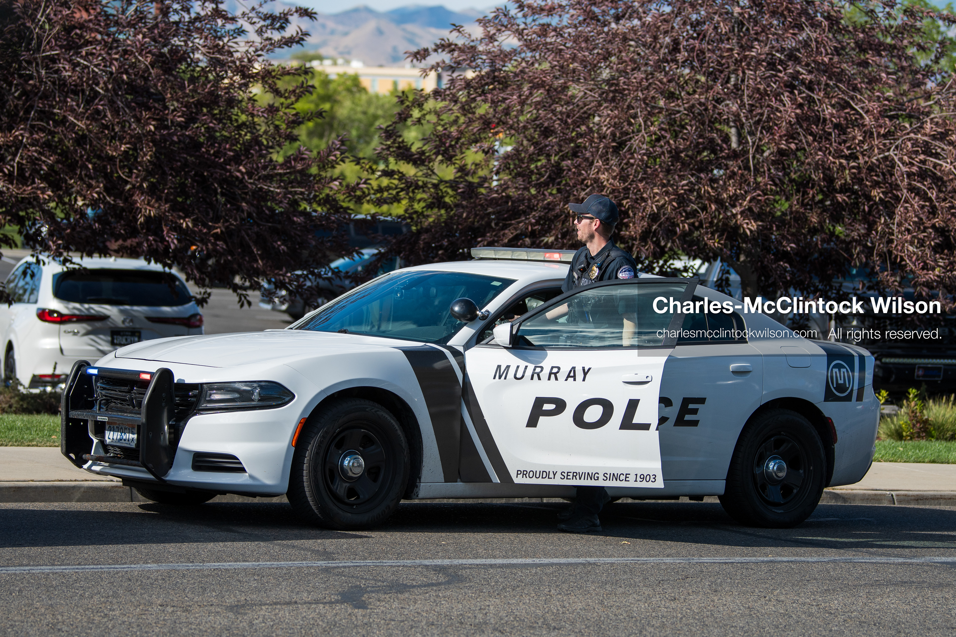 A Murray City Police officer stands behind the open driver-side door of a marked police cruiser parked outside Intermountain Medical Center in Murray, Utah, on Monday, August 17, 2026. Multiple regional law enforcement agencies converged to heavily secure the hospital perimeter as a safety precaution after shooting victims arrived from a fatal shootout that erupted outside a funeral service in nearby Kearns earlier that day. (Photo by Charles-McClintock Wilson/Sipa USA)