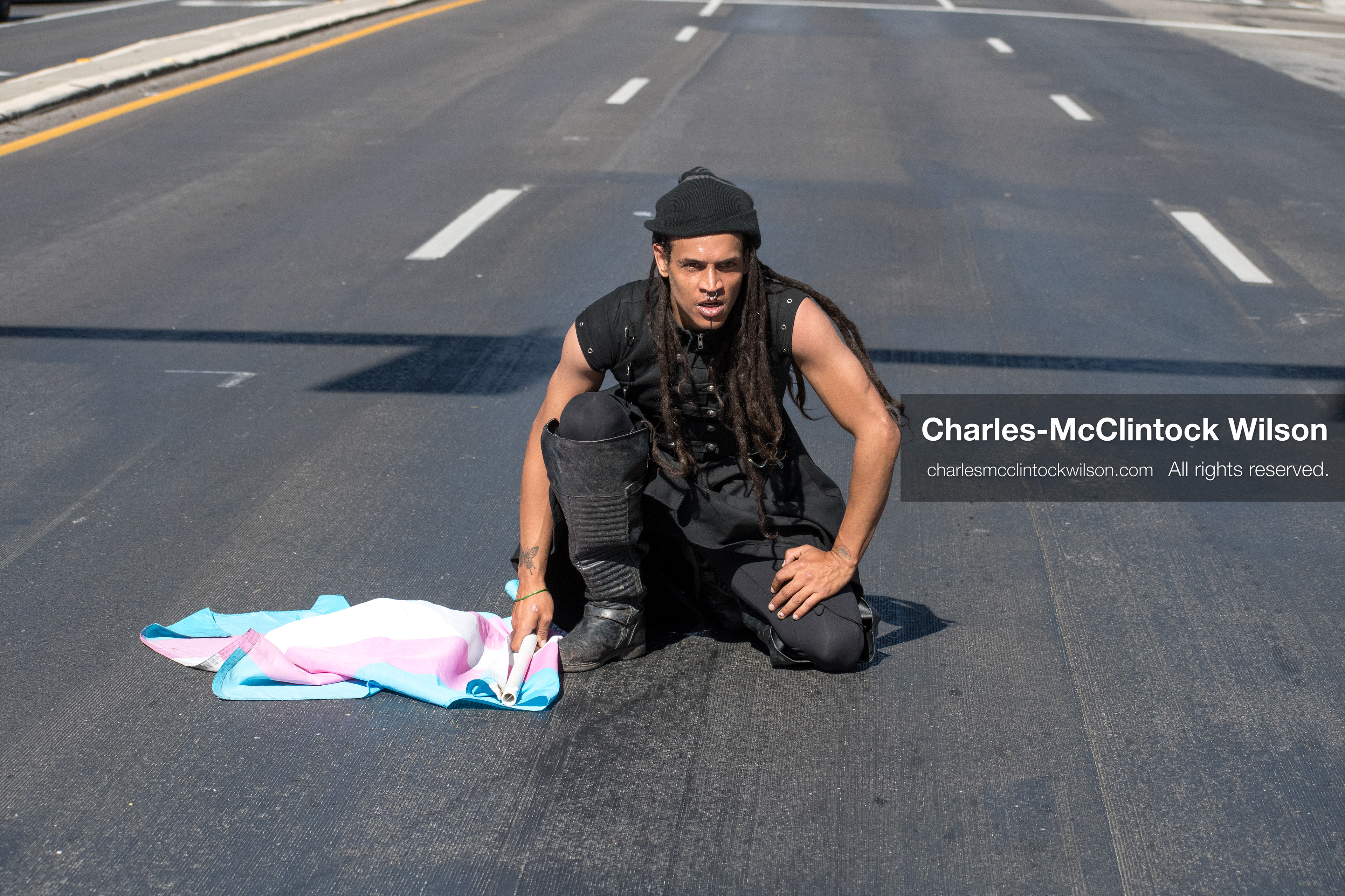 October 18, 2025, Salt Lake City, Utah, USA: A demonstrator kneels with a transgender pride flag during a "No Kings" protest in Salt Lake City, Utah. The protest was part of a nationwide mobilization.