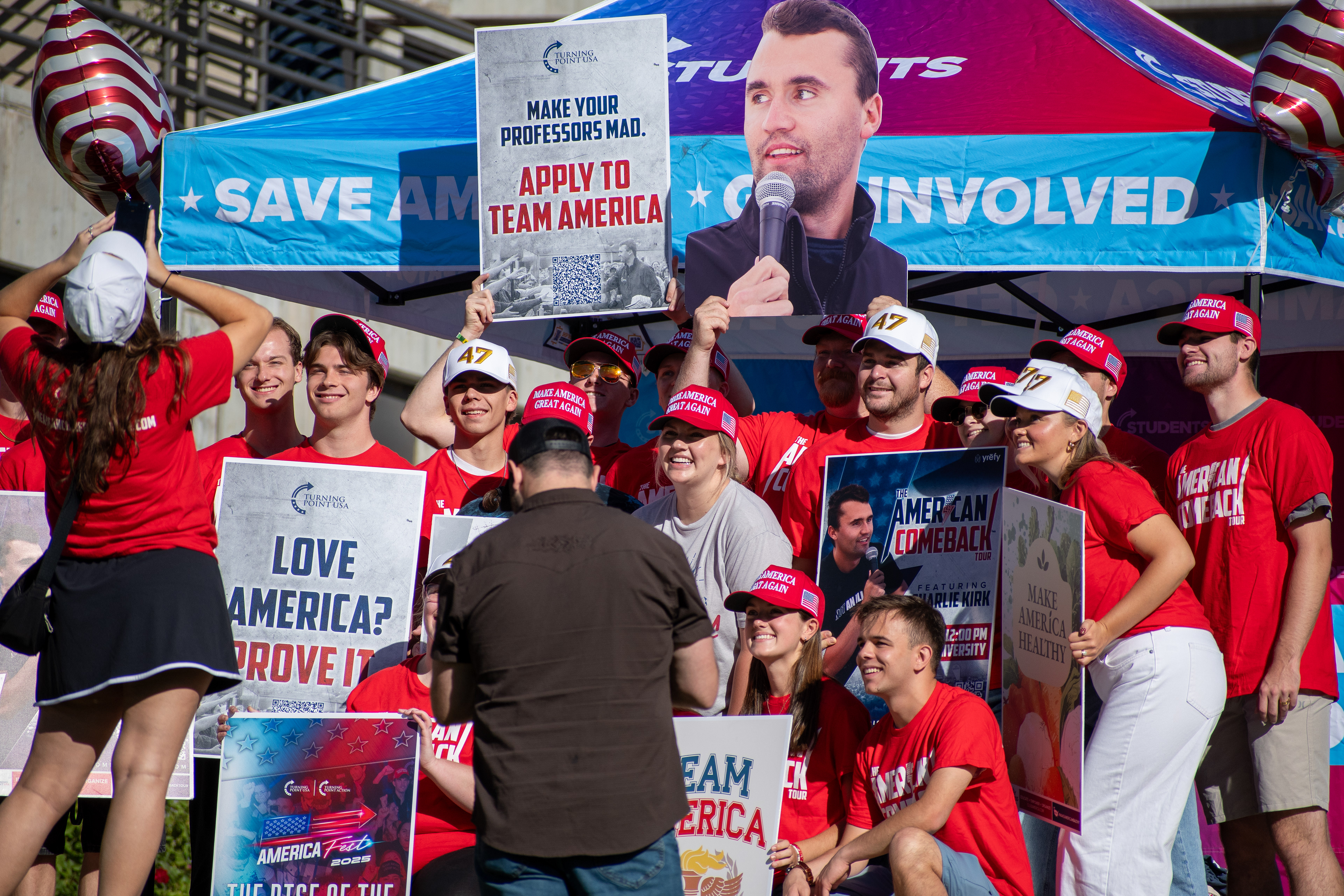 OREM, UTAH – SEPTEMBER 10, 2025: Attendees gather outside the Pope Science building at Utah Valley University during the opening stop of the American Comeback Tour. Surrounded by signage and coordinated attire, the group reflects a moment of thematic clarity, civic invitation, and communal energy. The image captures the rhythm of participation and the visual texture that shaped the event’s atmosphere. © Charles-McClintock Wilson / ZUMA Press