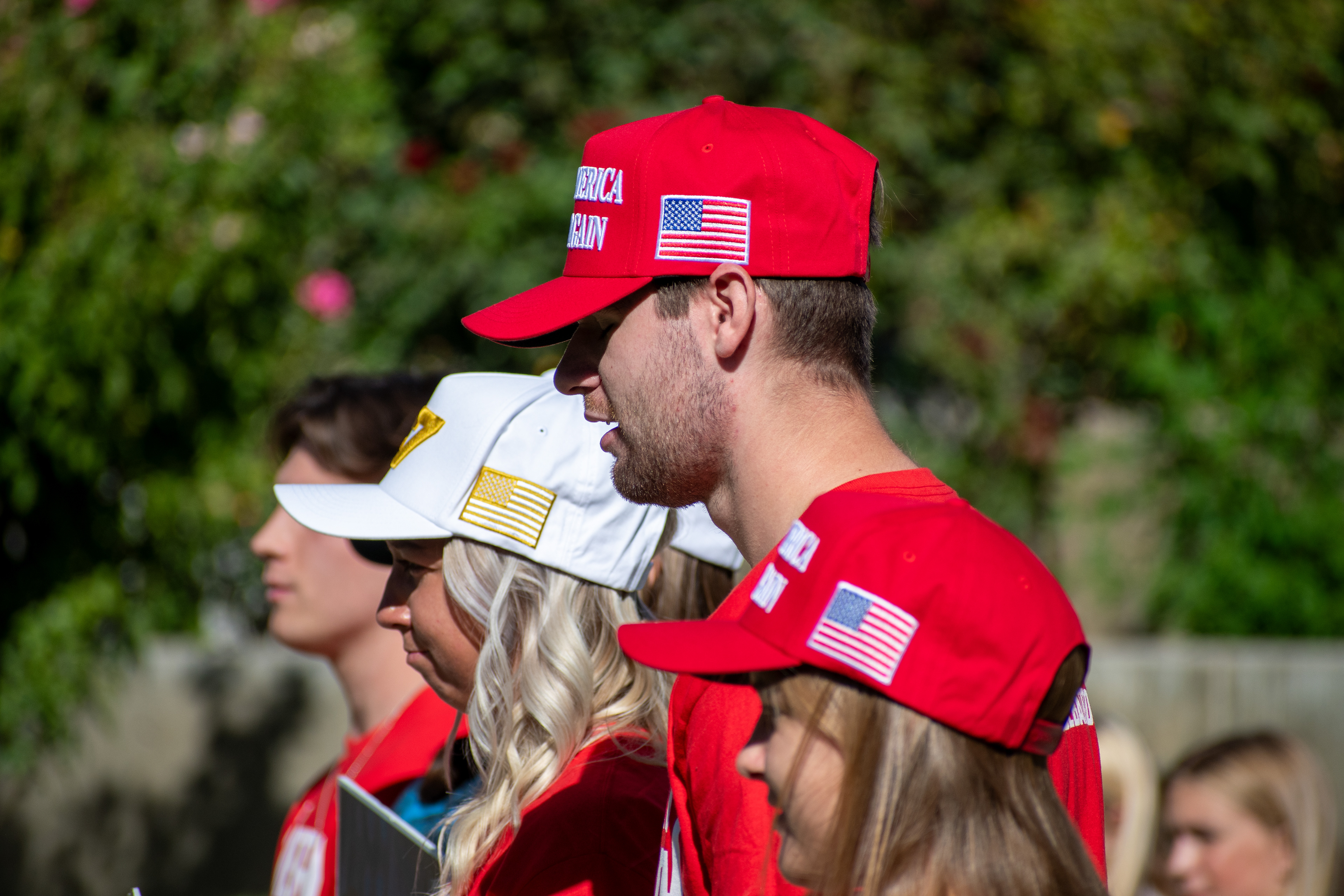  OREM, UTAH – SEPTEMBER 10, 2025: Attendees stand together near the greenery at Utah Valley University during the opening stop of the American Comeback Tour. Dressed in coordinated red shirts and caps, the group reflects a moment of visual unity, civic presence, and quiet anticipation. The image captures the communal rhythm and symbolic texture that shaped the atmosphere of the day. © Charles-McClintock Wilson / ZUMA Press