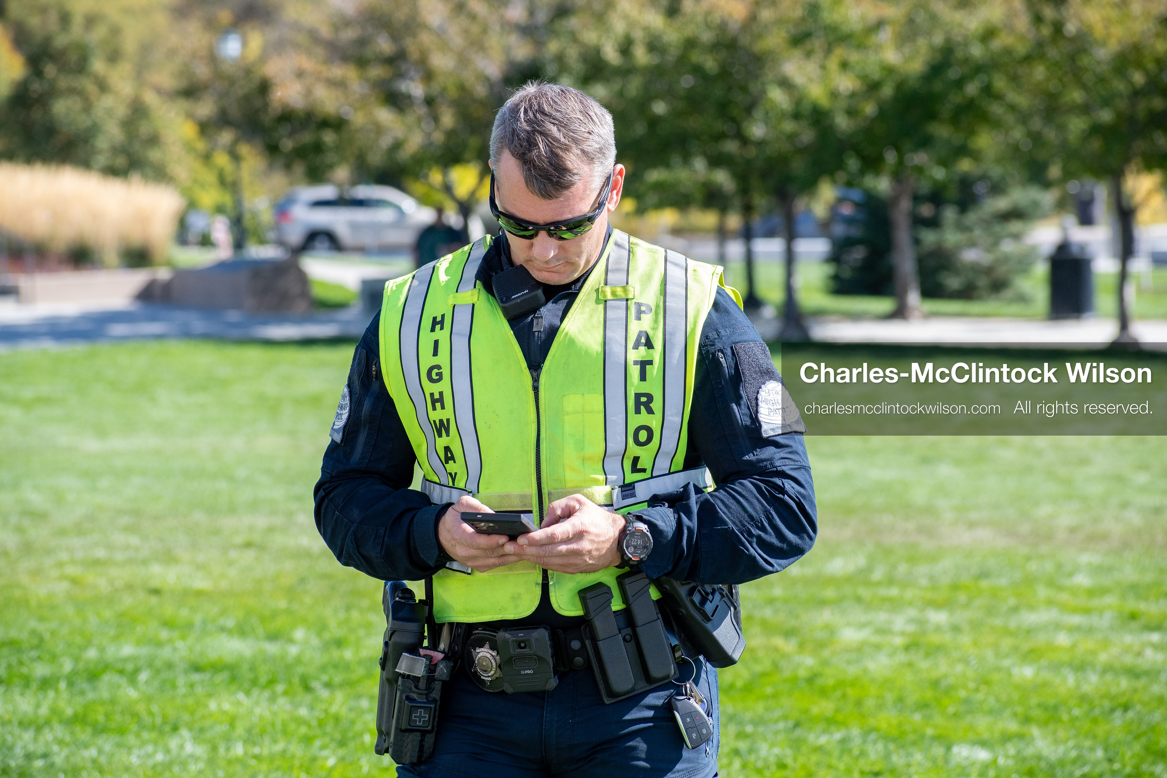 Salt Lake City, Utah, U.S., October 18, 2025: A Utah Highway Patrol officer looks down at a mobile device during a “No Kings” protest at the Utah State Capitol. The demonstration, organized in opposition to U.S. President Donald Trump’s administration, called for restraint in executive power and rejected personality-driven governance.