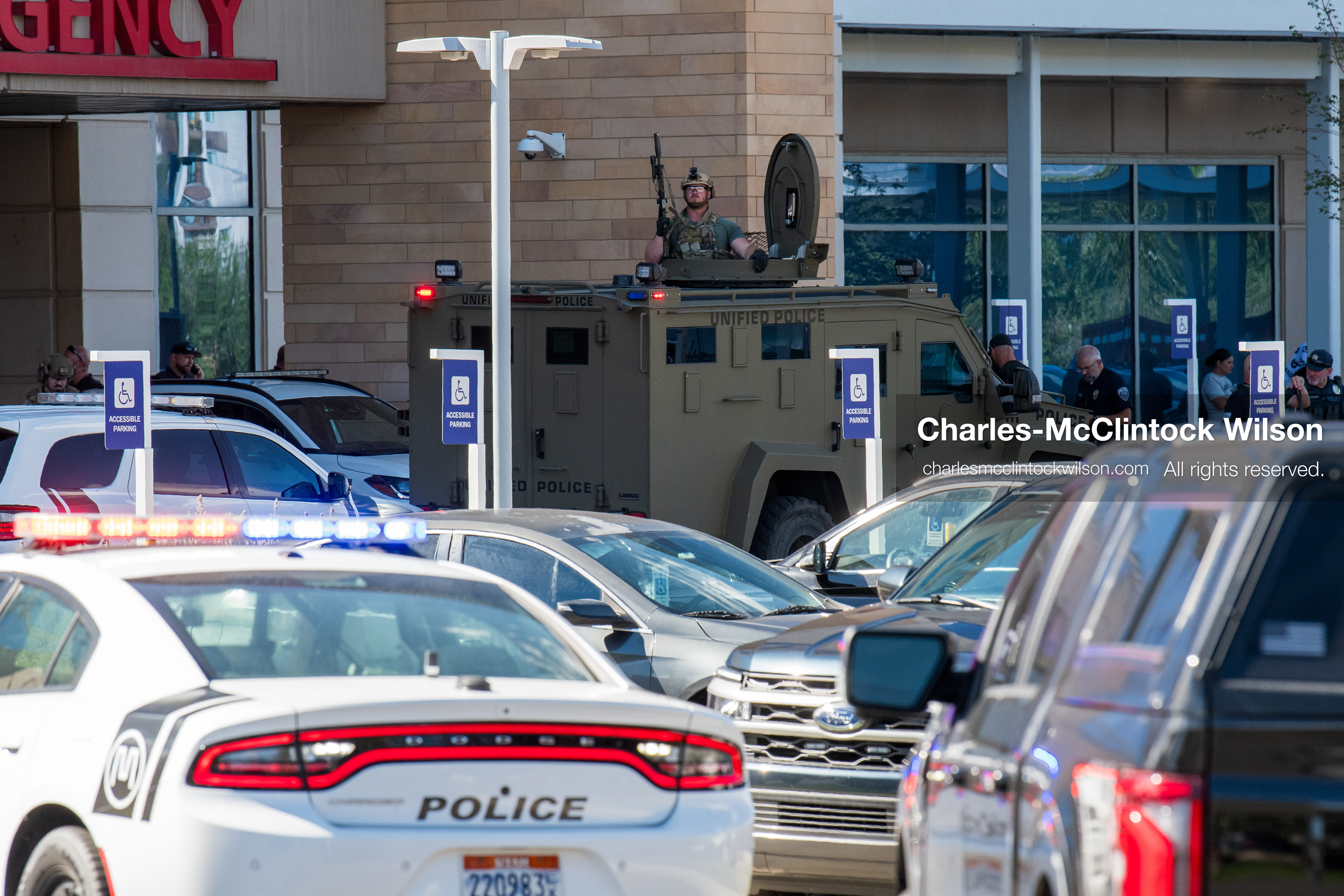 An armored tactical vehicle sits positioned near the emergency department entrance as police cruisers line the parking lot at Intermountain Medical Center in Murray, Utah, on Monday, August 17, 2026. Multiple regional law enforcement agencies converged to heavily secure the hospital perimeter as a safety precaution after shooting victims arrived from a fatal shootout that erupted outside a funeral service in nearby Kearns earlier that day. (Photo by Charles-McClintock Wilson/Sipa USA)