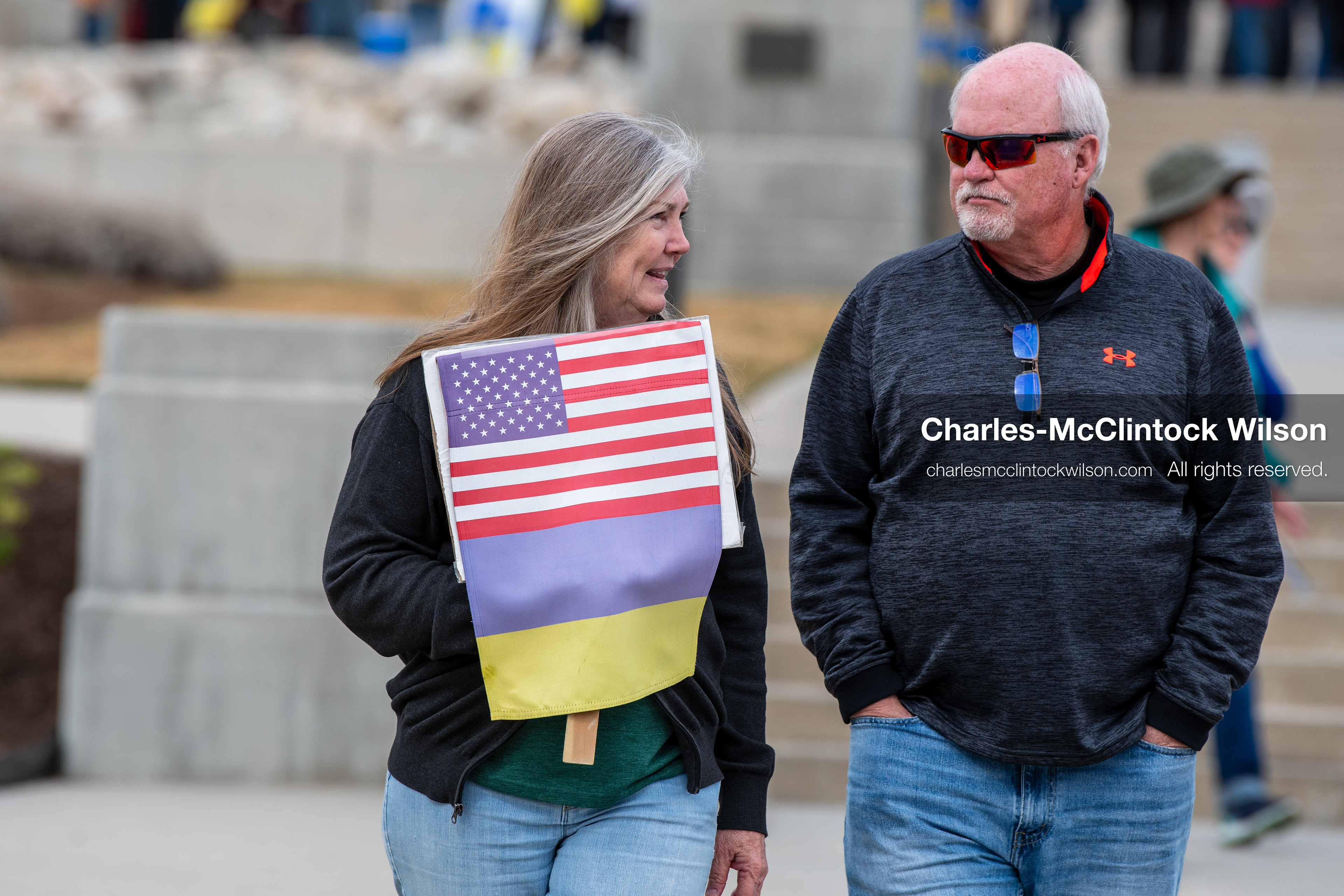 February 28, 2026, Salt Lake City, Utah, USA: Two demonstrators walk near the Utah State Capitol during the Stand With Ukraine rally, one carrying a sign featuring combined U.S. and Ukrainian flag imagery. The gathering marked the four year anniversary of the full scale Russian invasion of Ukraine and brought community members together in support of Ukrainians and local humanitarian efforts. (Credit Image: © Charles McClintock Wilson/ZUMA Press Wire)