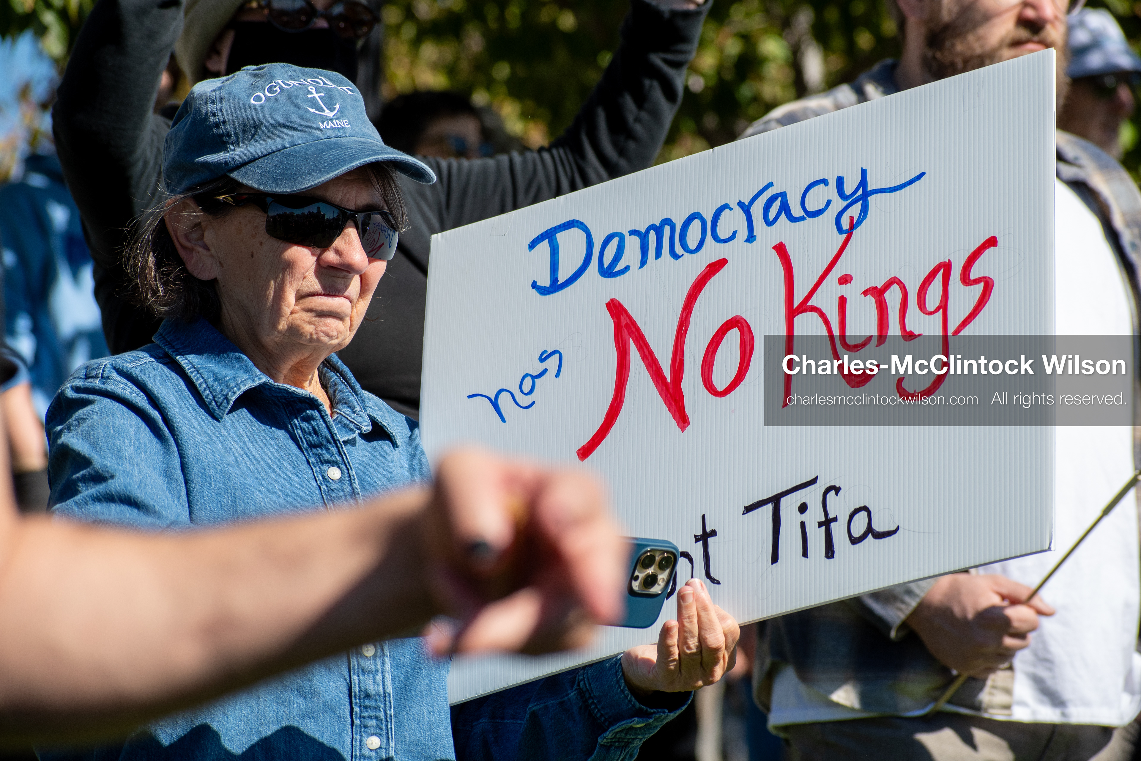 October 18, 2025, Salt Lake City, Utah, USA: A demonstrator raises a placard during a "No Kings" protest held at the Utah State Capitol. Other participants and signs are visible in the background during the public gathering.