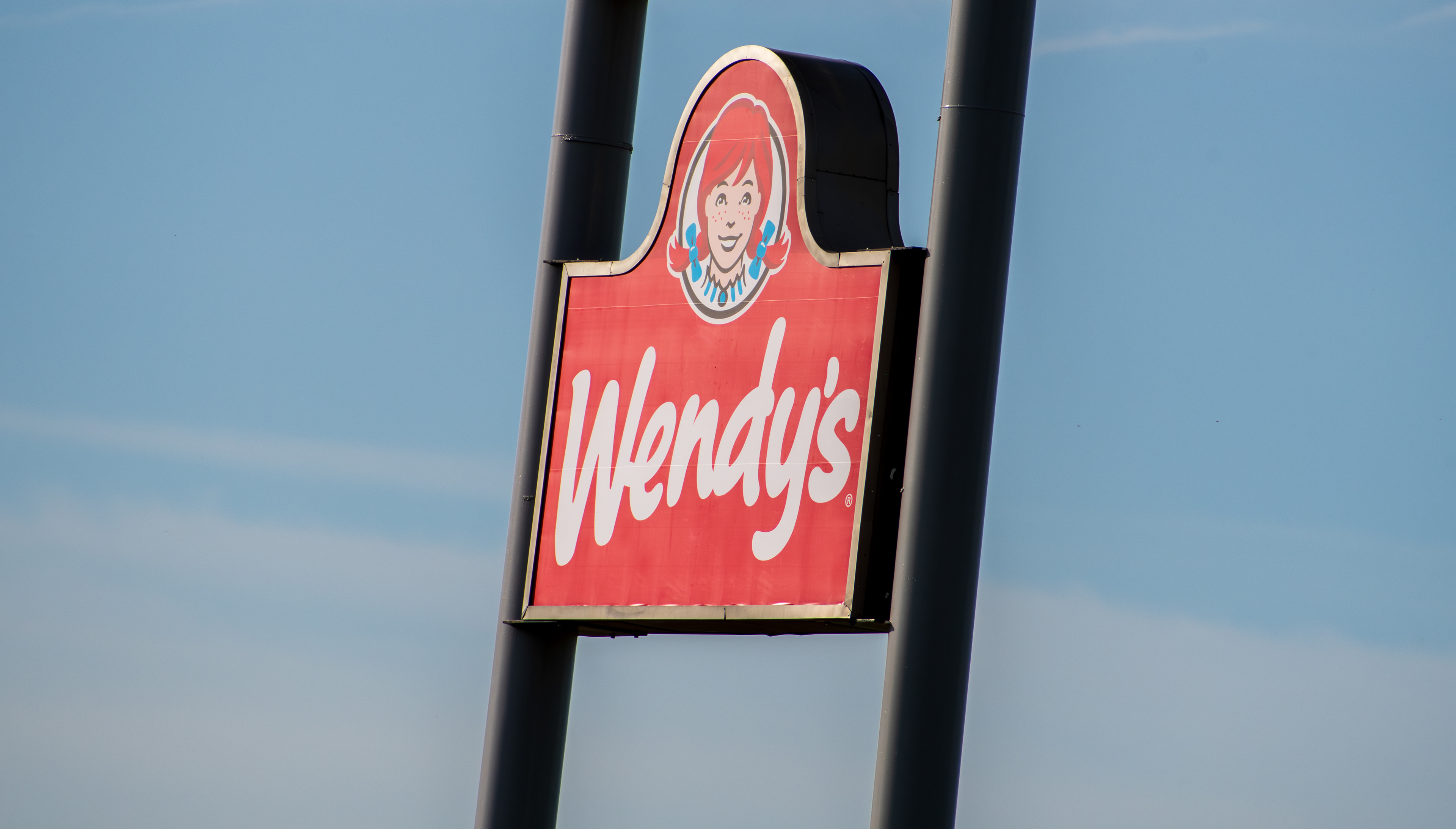 Spanish Fork, Utah, USA – May 28, 2025: A Wendy’s sign stands tall along Interstate 15 in Spanish Fork, Utah, serving as a recognizable marker for the fast-food chain near the busy highway.