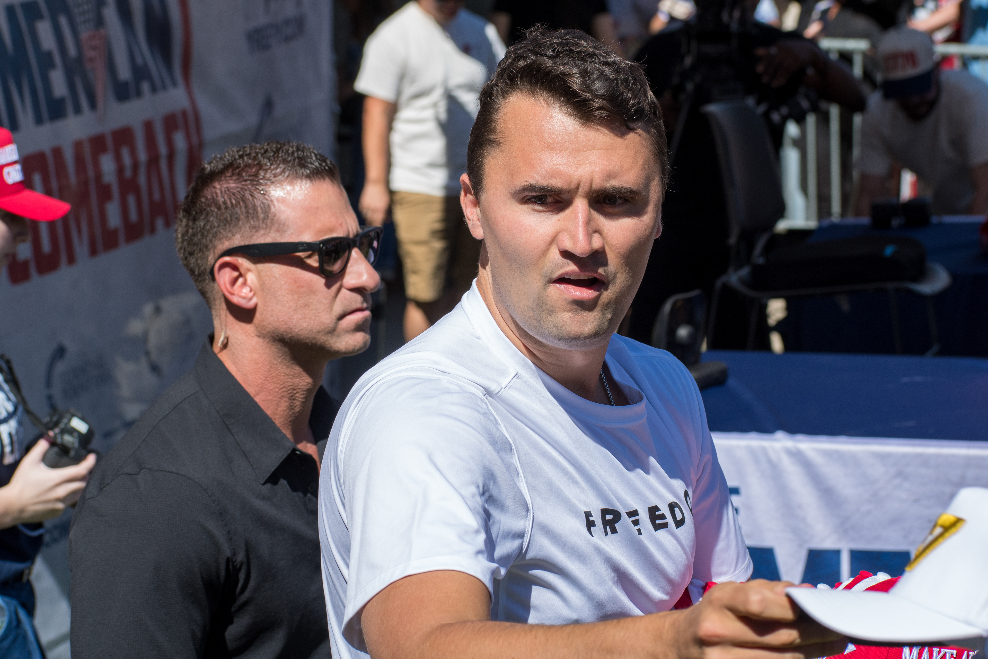 OREM, UTAH – SEPTEMBER 10, 2025: Charlie Kirk holds several “Make America Great Again” hats while interacting with supporters during a public event at Utah Valley University. Positioned near a merchandise table and surrounded by attendees, Kirk engages directly with the crowd in one of his final public moments. The image reflects the branding, outreach, and political symbolism that defined the gathering. © Charles-McClintock Wilson / ZUMA Press