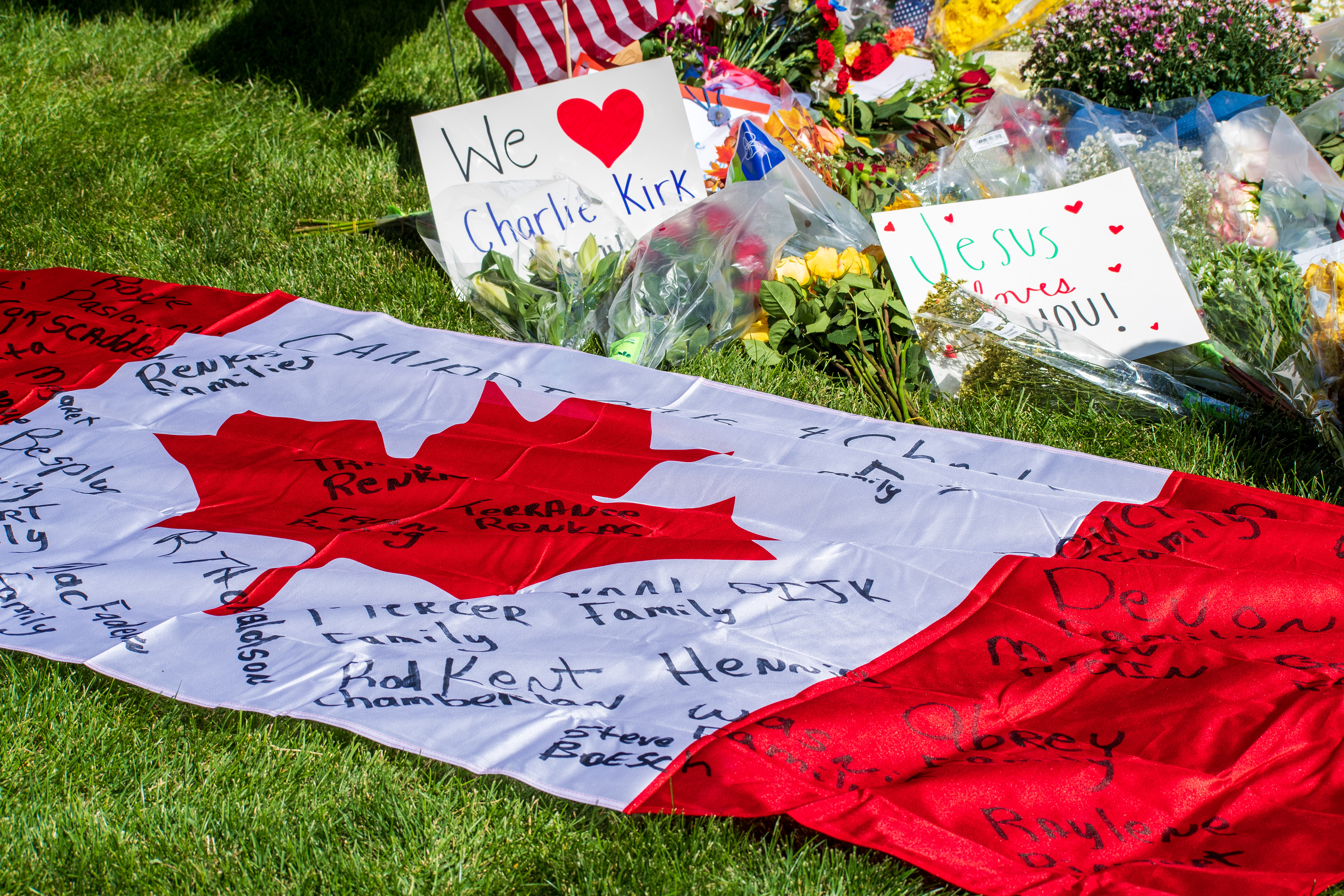OREM, UTAH – SEPTEMBER 12, 2025: A Canadian flag signed by mourners is laid out on the grass at a memorial site for Charlie Kirk near Utah Valley University. Surrounded by flowers, handwritten posters, and small American flags, the tribute reflects a cross-national gesture of remembrance. © Charles‑McClintock Wilson / ZUMA Press