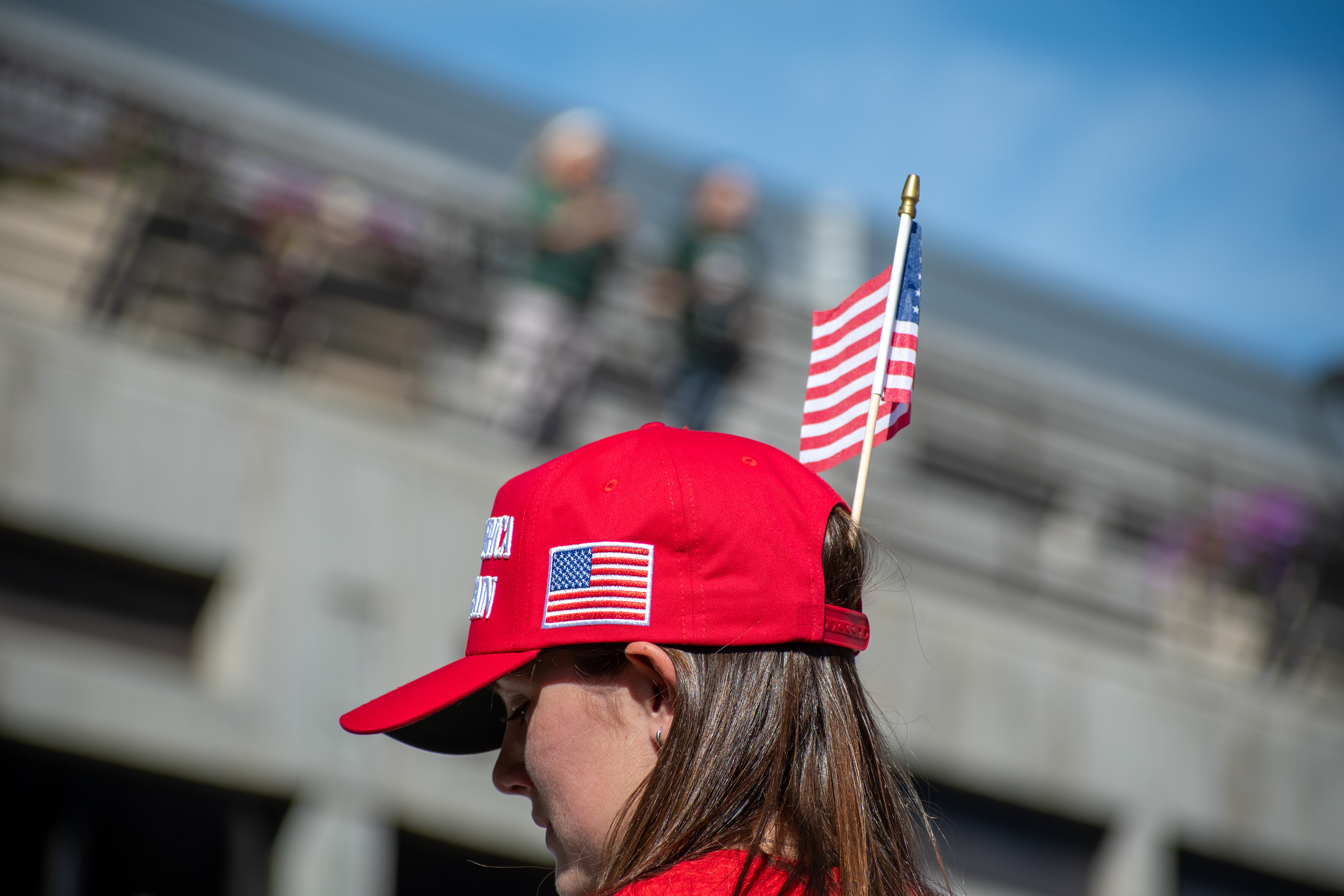 OREM, UTAH – SEPTEMBER 10, 2025: An attendee stands near the event perimeter at Utah Valley University during the opening stop of the American Comeback Tour. Dressed in red and framed against a clear sky, the individual reflects a moment of personal expression and quiet anticipation. The image captures the symbolic texture and civic presence that shaped the atmosphere of the day. © Charles-McClintock Wilson / ZUMA Press