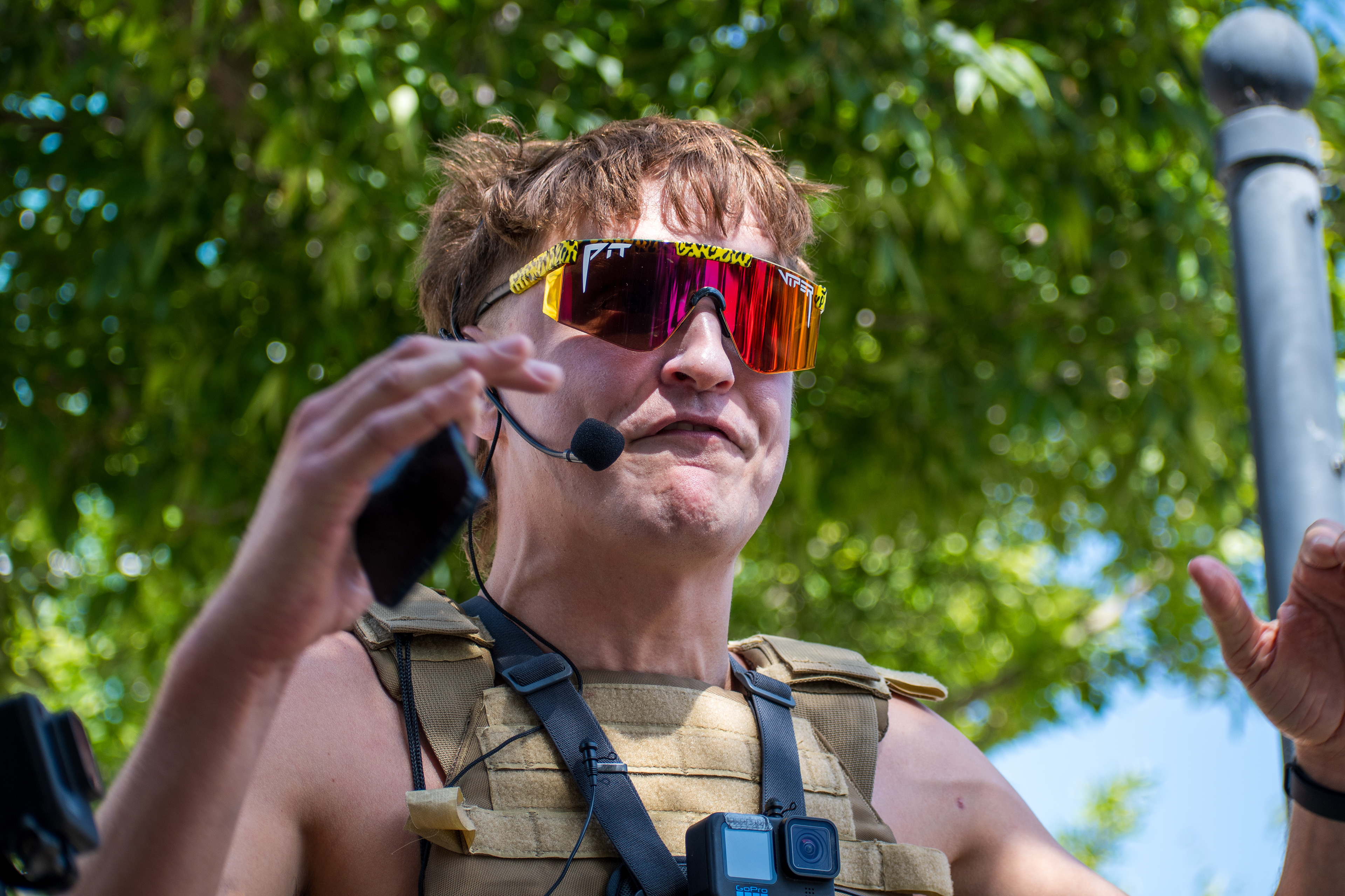 September 15, 2025 – Provo, Utah, United States: A demonstrator speaks emphatically into a headset microphone outside the Utah Valley Convention Center during a protest against the Department of Homeland Security career expo. Reflective “Pit Viper” sunglasses and a mullet hairstyle add visual intensity to the moment of civic expression. Photograph by Charles‑McClintock Wilson / ZUMA Press Wire