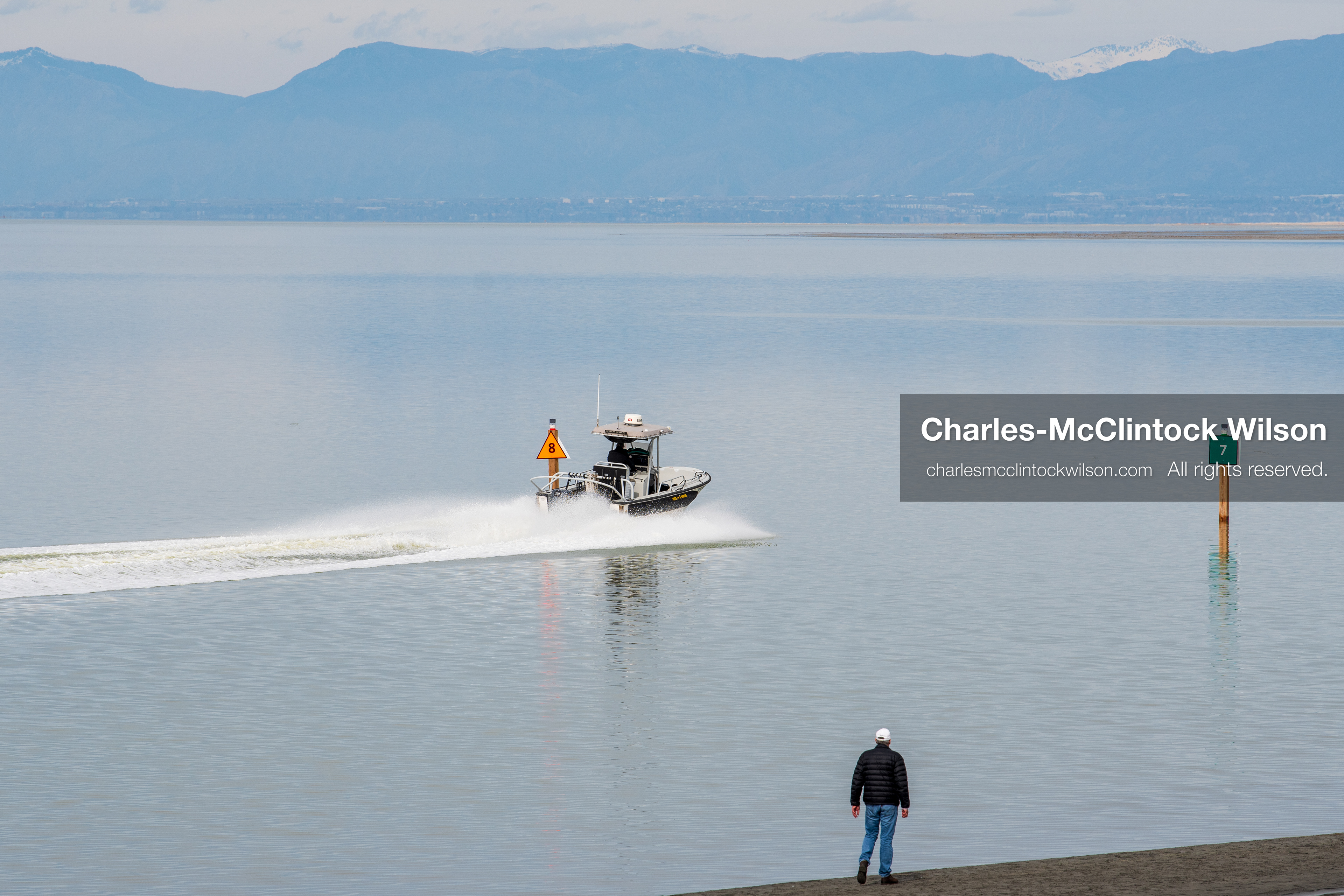 March 1, 2026, Great Salt Lake, Utah, USA: A person stands along the shoreline of the Great Salt Lake while a boat moves through a marked channel as water levels in the region remain historically low. Reports from state officials and the Great Salt Lake Strike Team state that the lake continues to fall within a serious adverse‑effects range, with elevations among the lowest recorded in more than one hundred years. The lake has drawn increased public attention as lawmakers consider large‑scale water projects and long‑term plans to address declining conditions. (Credit Image: © Charles‑McClintock Wilson/ZUMA Press Wire)